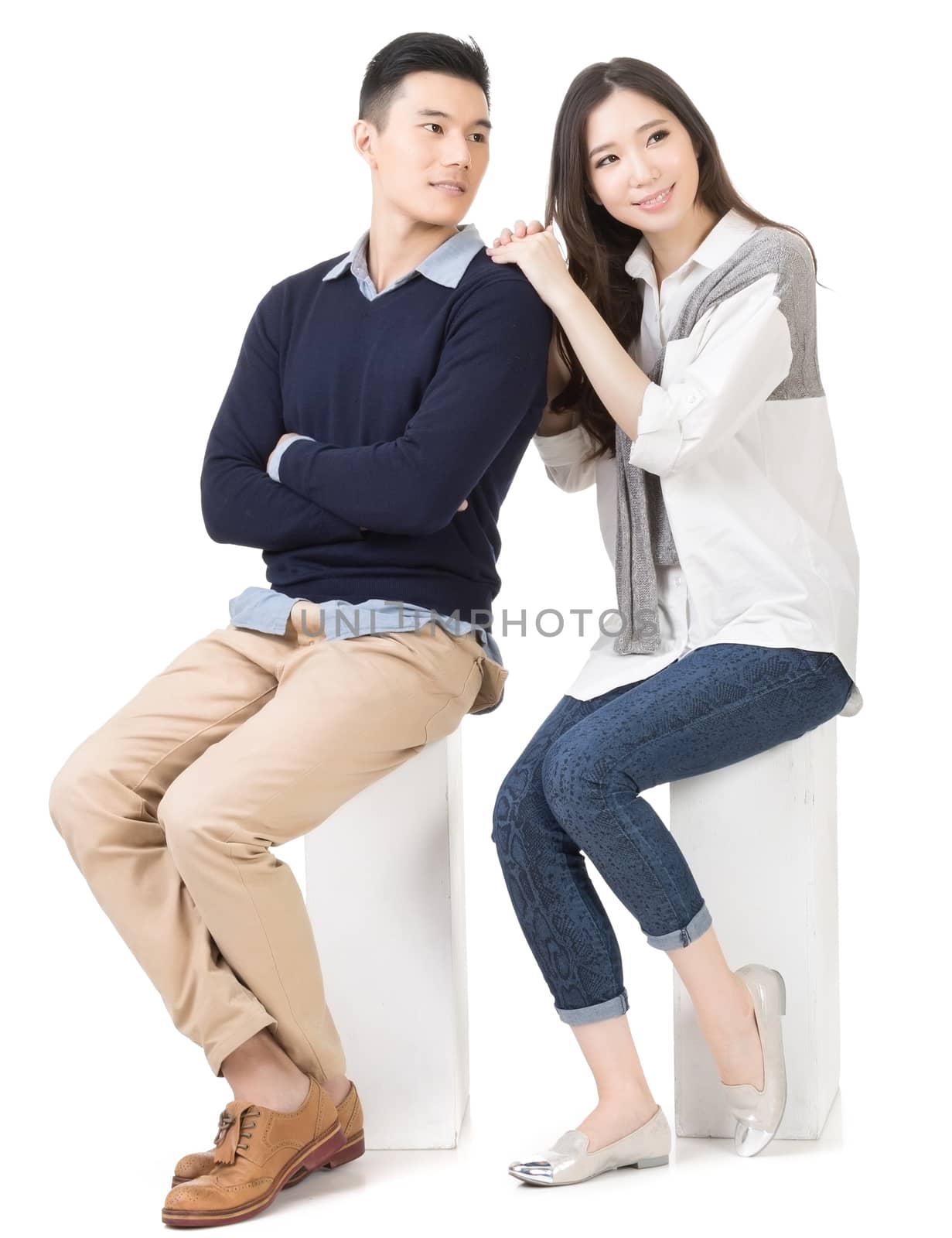 Portrait of young attractive Asian couple sitting on a box, full length portrait isolated on white background.