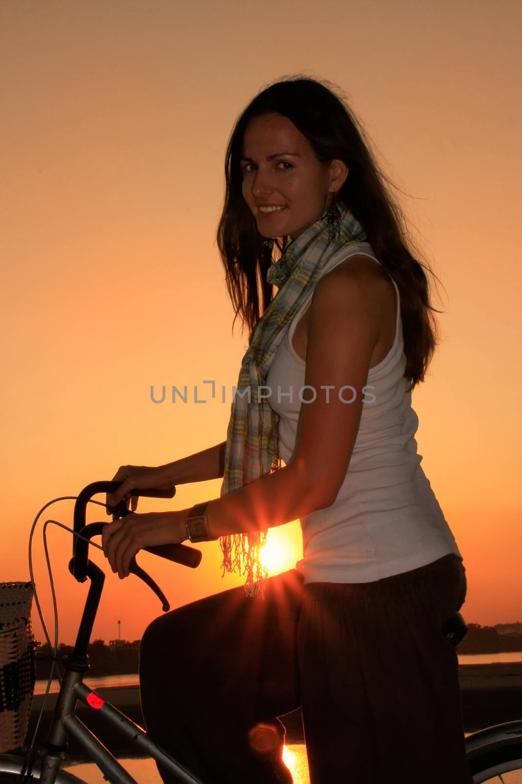 Silhouetted woman with bicycle at Mekong river waterfront at sunset, Vientiane, Laos, Southeast Asia