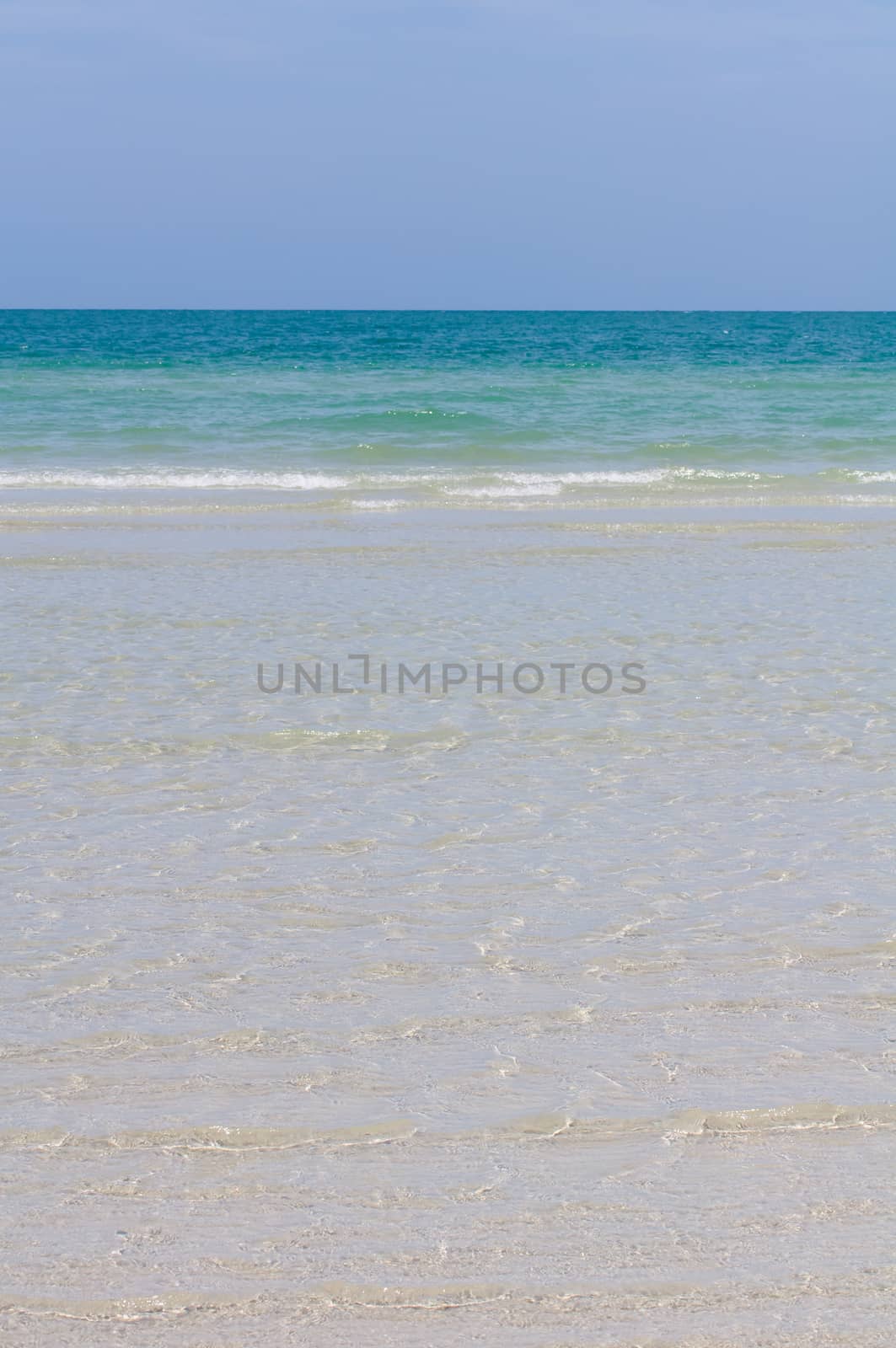 Sea with waves sandy coastline and deep blue sky