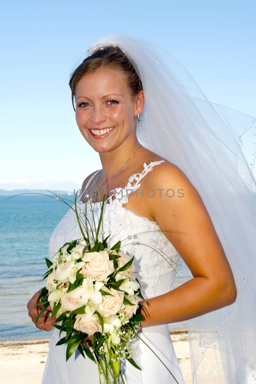 Happy wedding bride is holding a bouquet and is smiling.