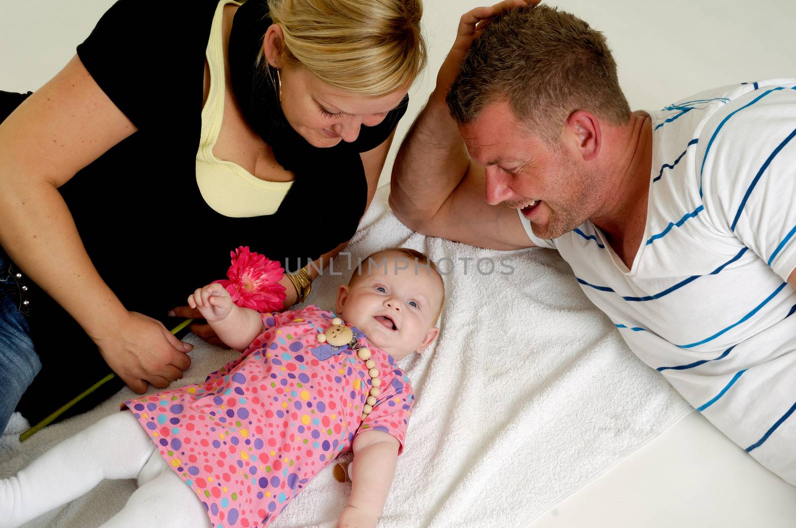 Mother and father are looking at their sweet smiling 4 month old baby.