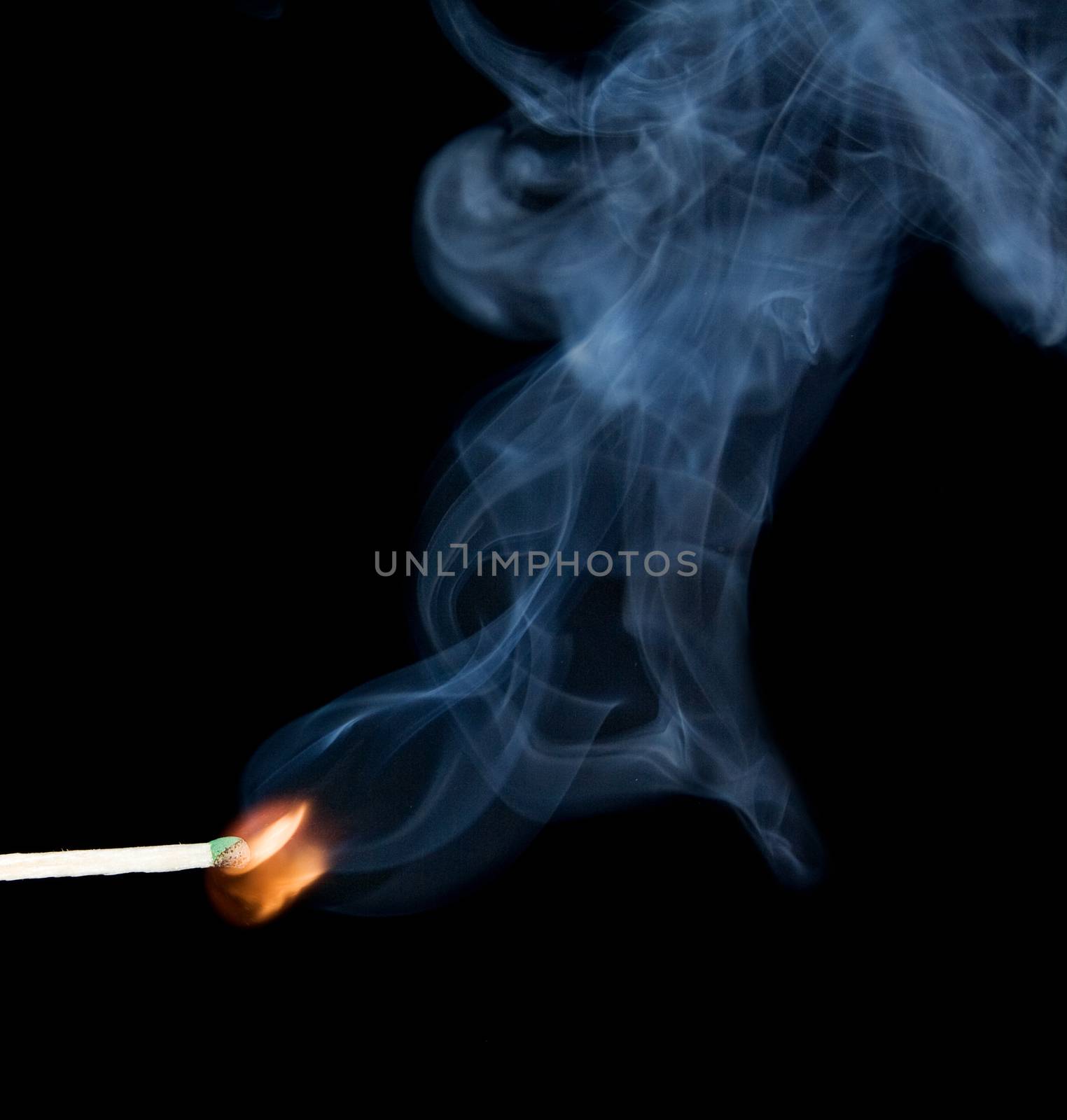 Lighted match and blue smoke on a black background