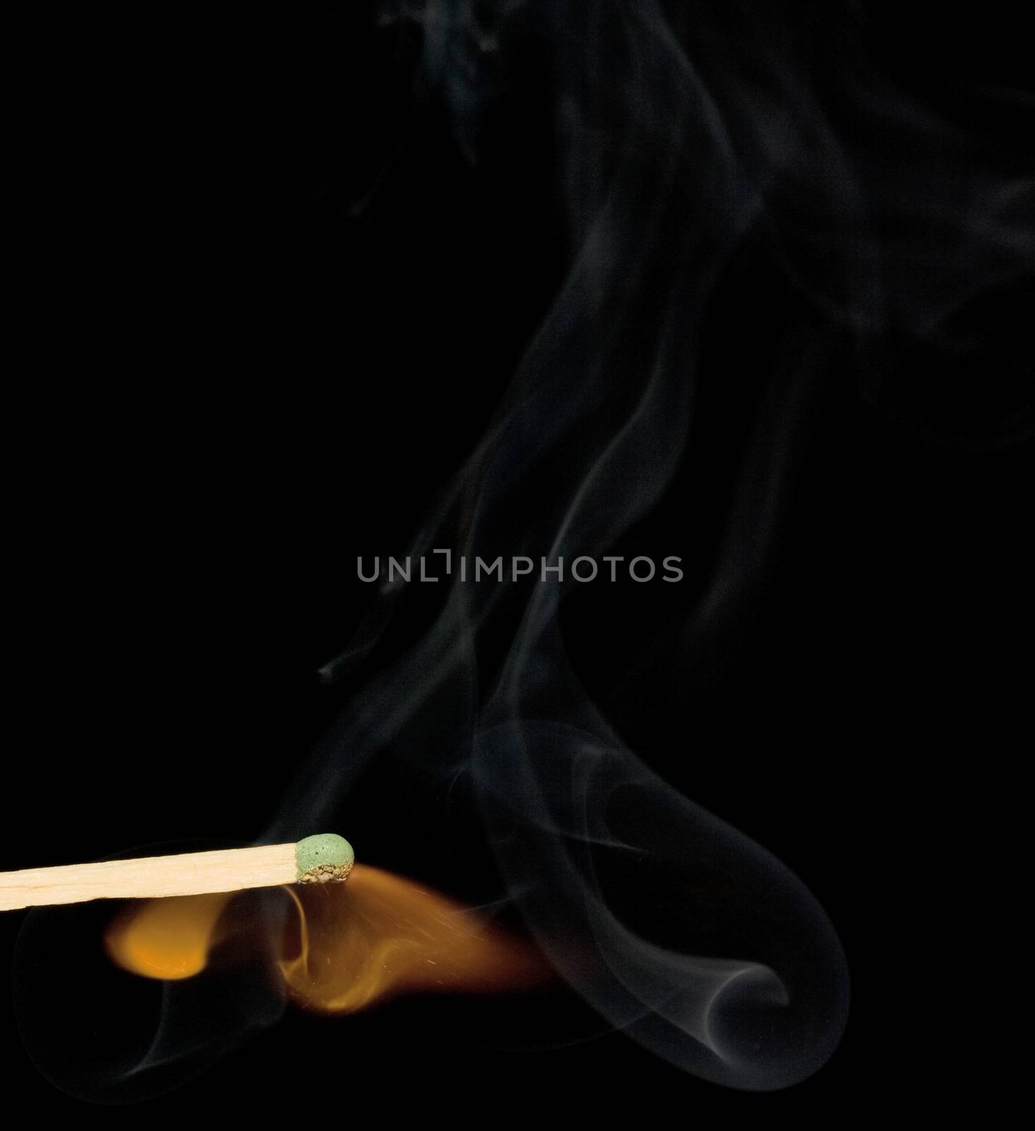 Lighted match and blue smoke on a black background.