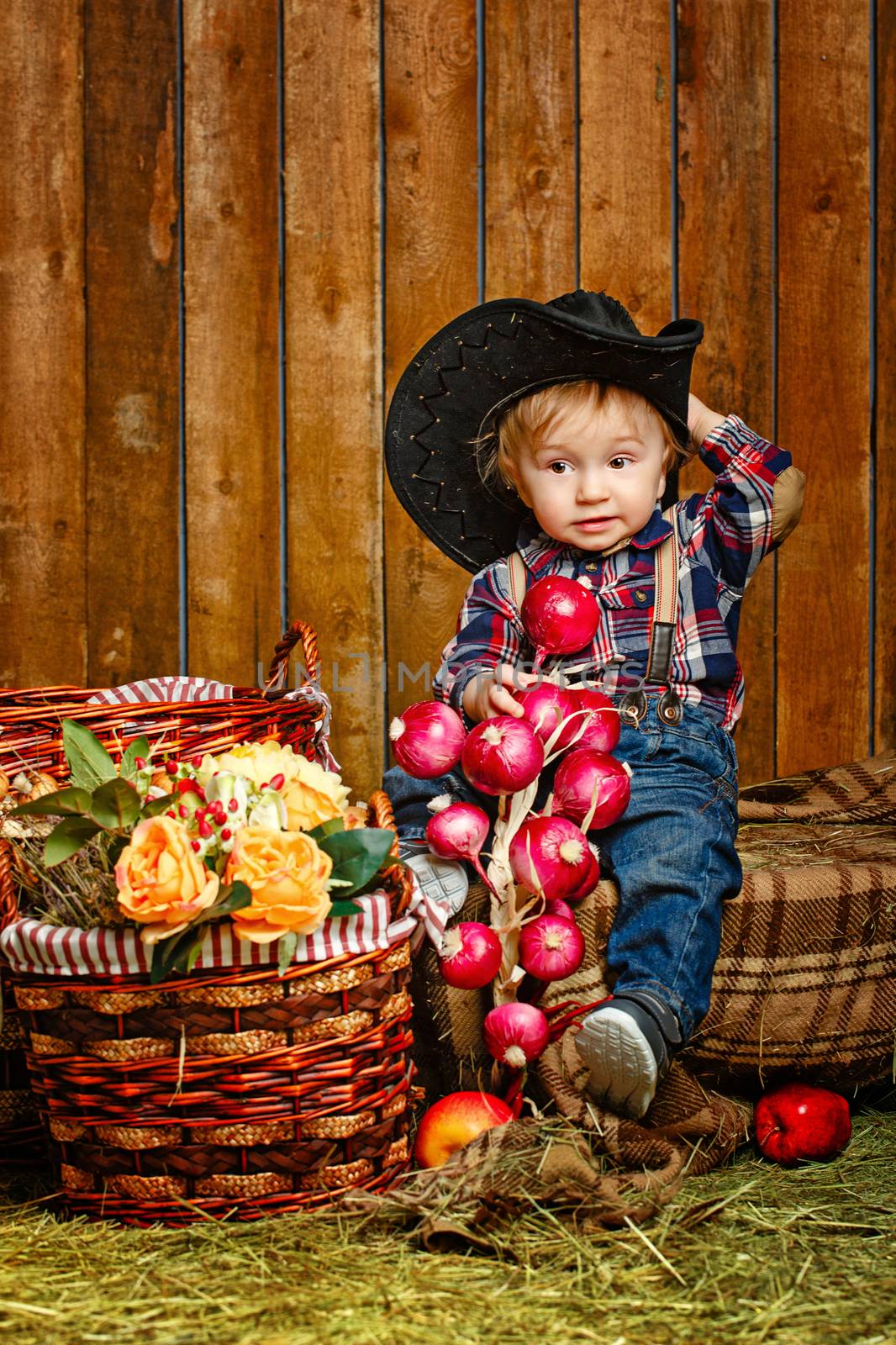 Little Cowboy on a farm in a hat and jeans after harvest
