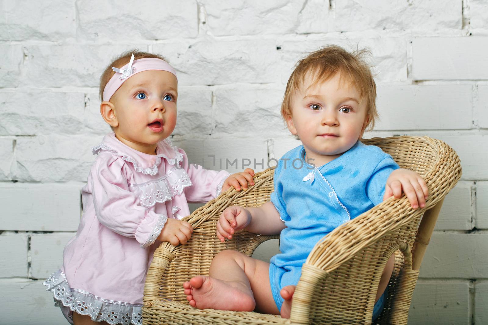 Brother and sister playing in the backyard next to the wicker chair