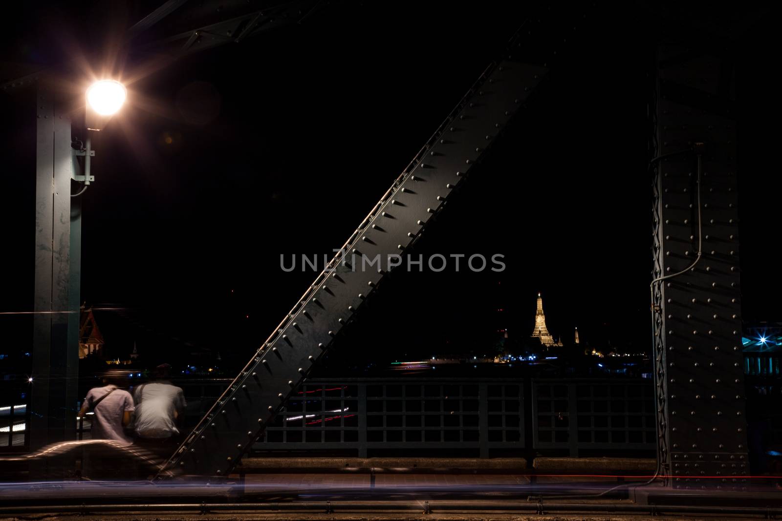 Couple sitting by the road. Under a light one. Romantic at night.