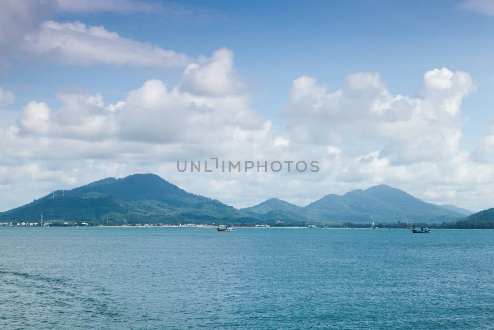 Mountains, sea and sky on a clear day atmosphere. A small boat sailing in the sea.