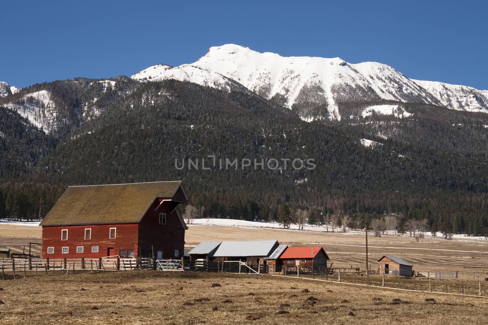 A red barn in early morning on the ranch against high mountain landscape