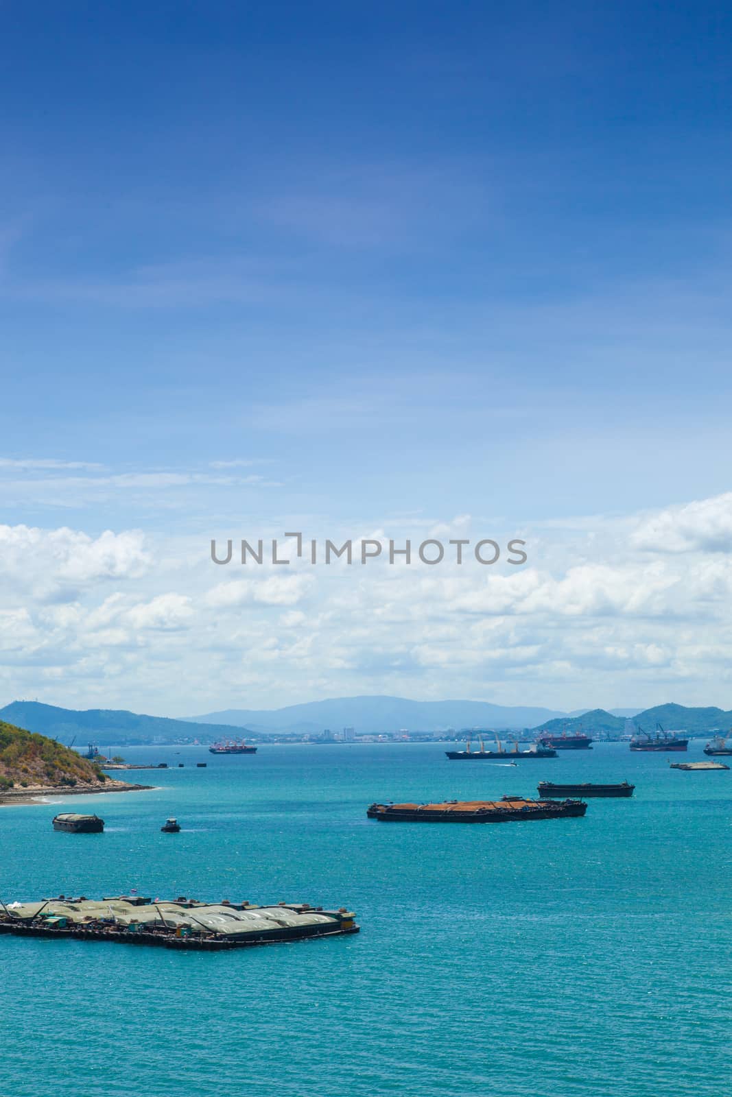 Cargo ships. Moored in the sea near the island. The bright sky in the daytime.
