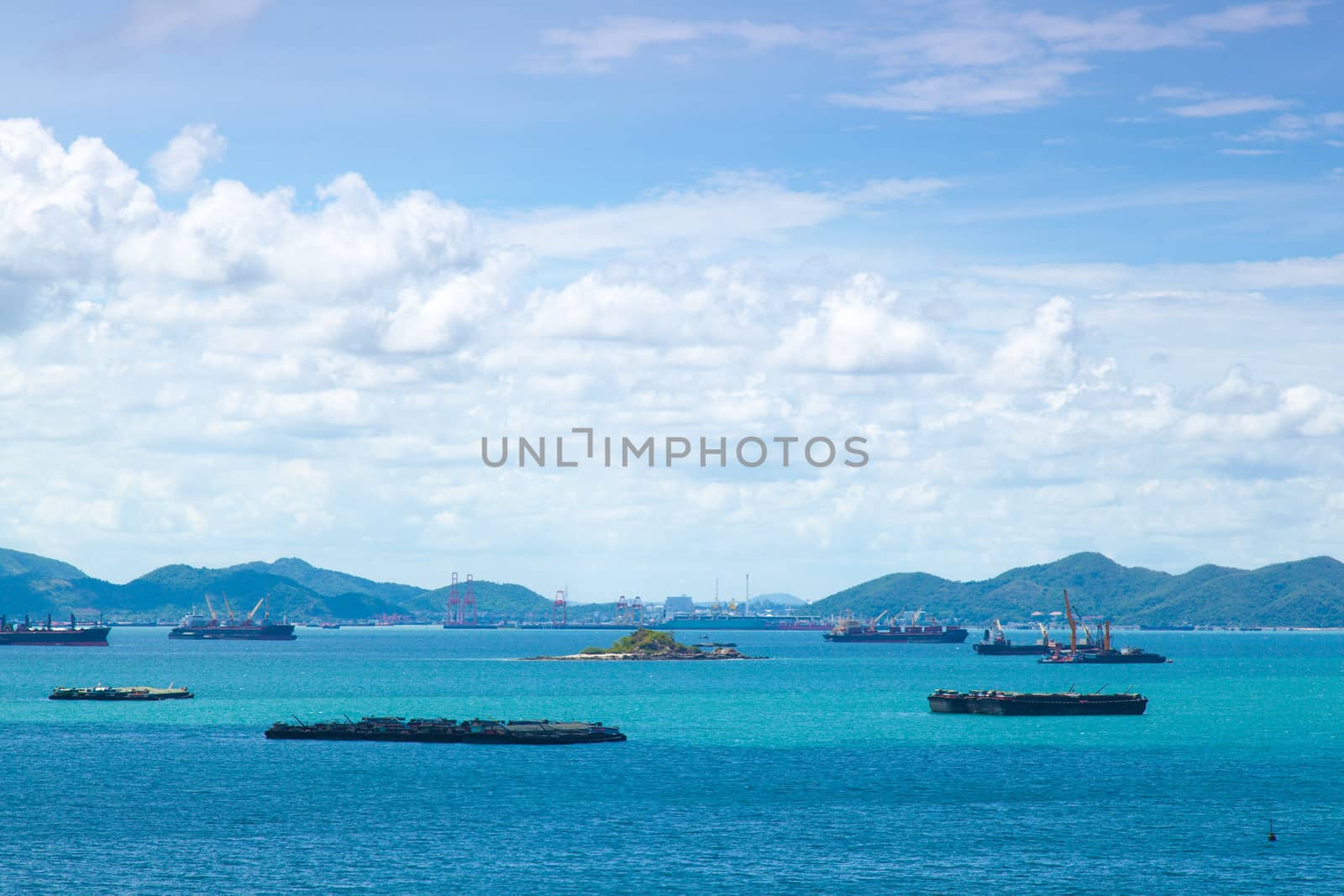Cargo ships. Moored in the sea near the island. The bright sky in the daytime.