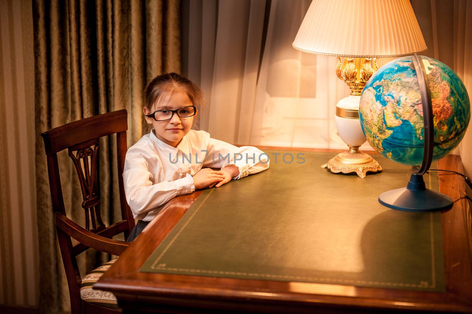 Girl in eyeglasses sitting behind table at cabinet by Kryzhov