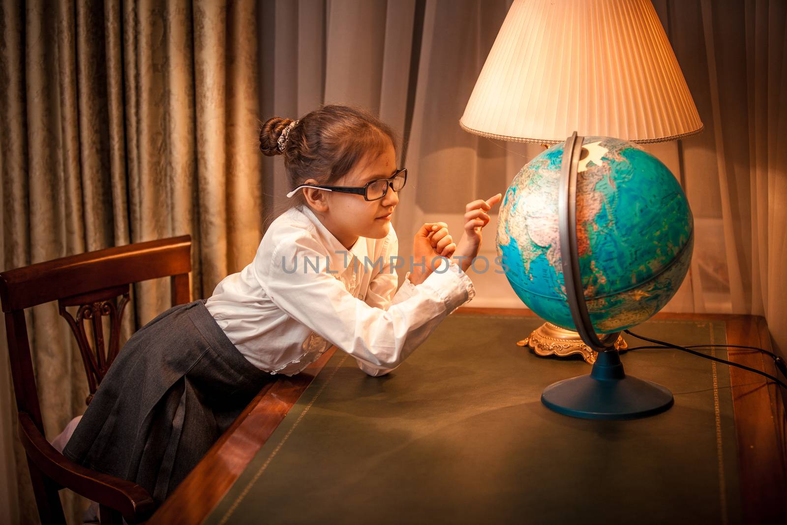 Little girl looking patiently at globe in classic interior