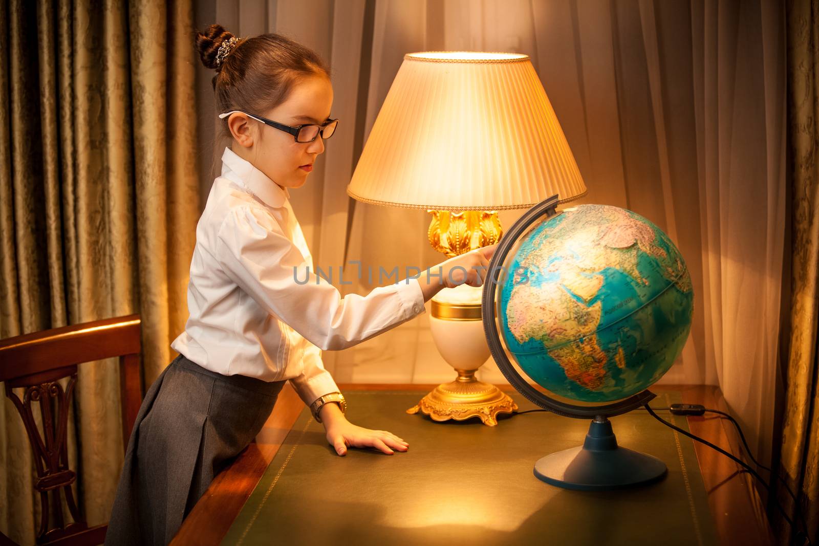 Young schoolgirl studying globe at desk