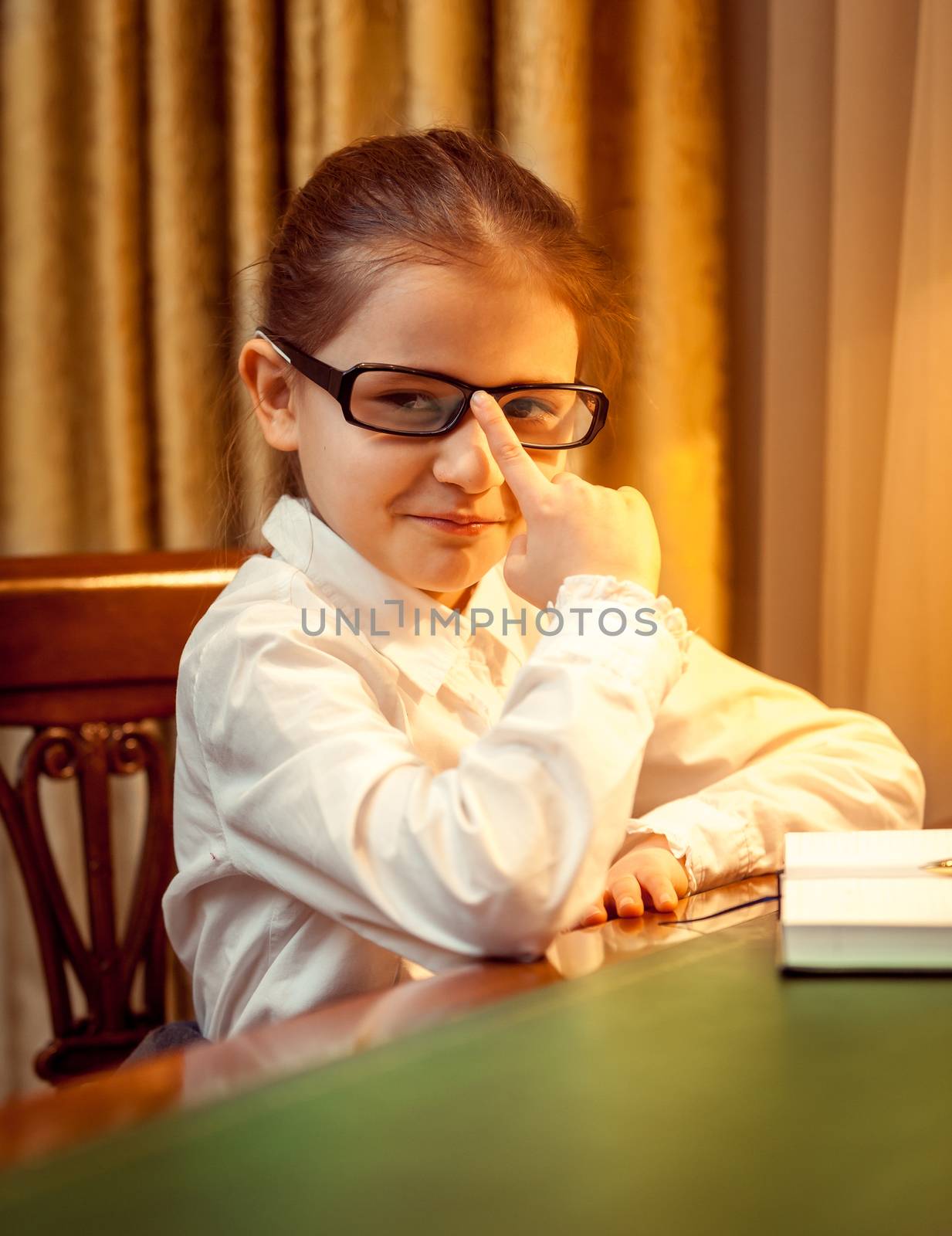 Young girl in eyeglasses sitting behind desk by Kryzhov