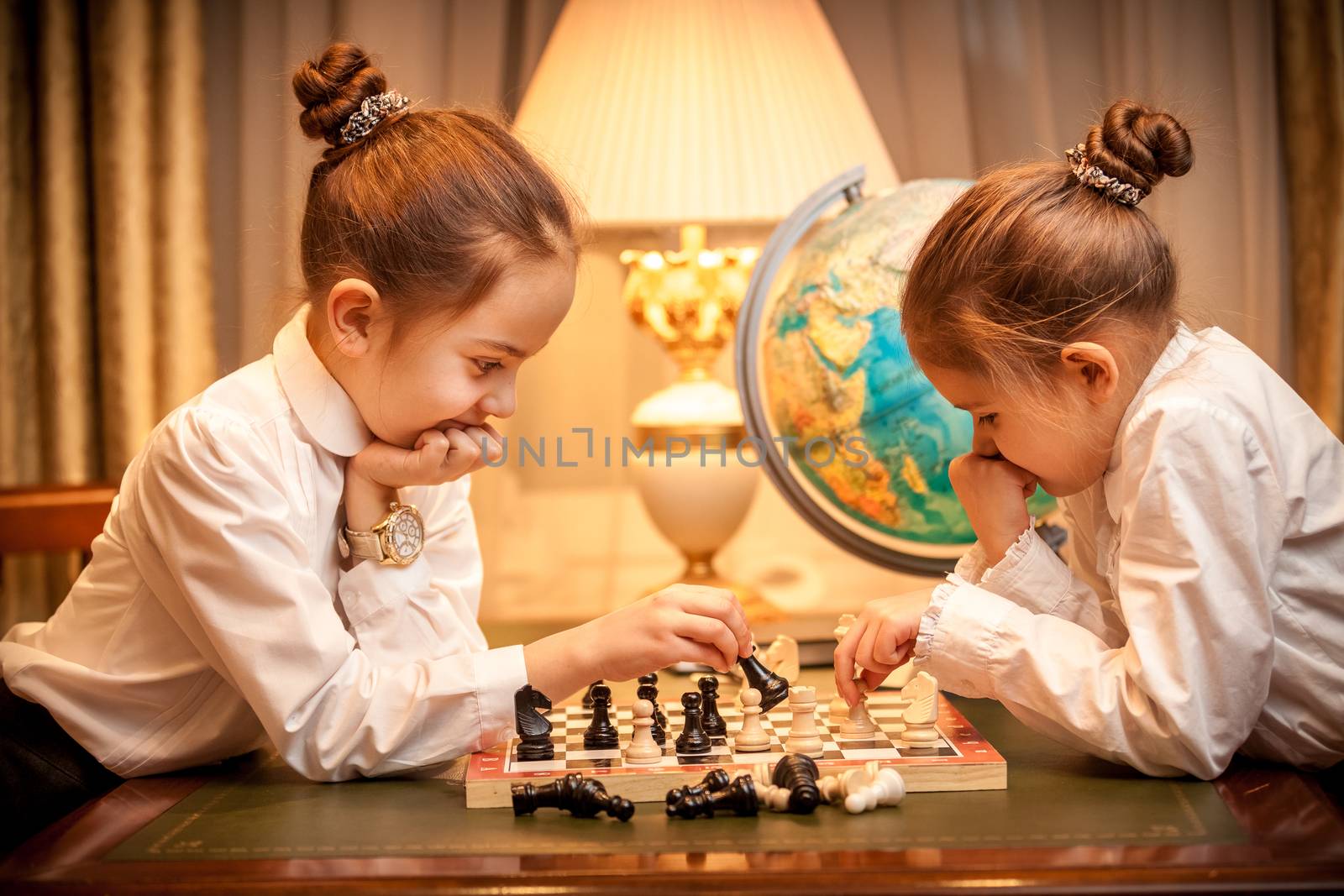 Girls in school uniform playing chess at cabinet