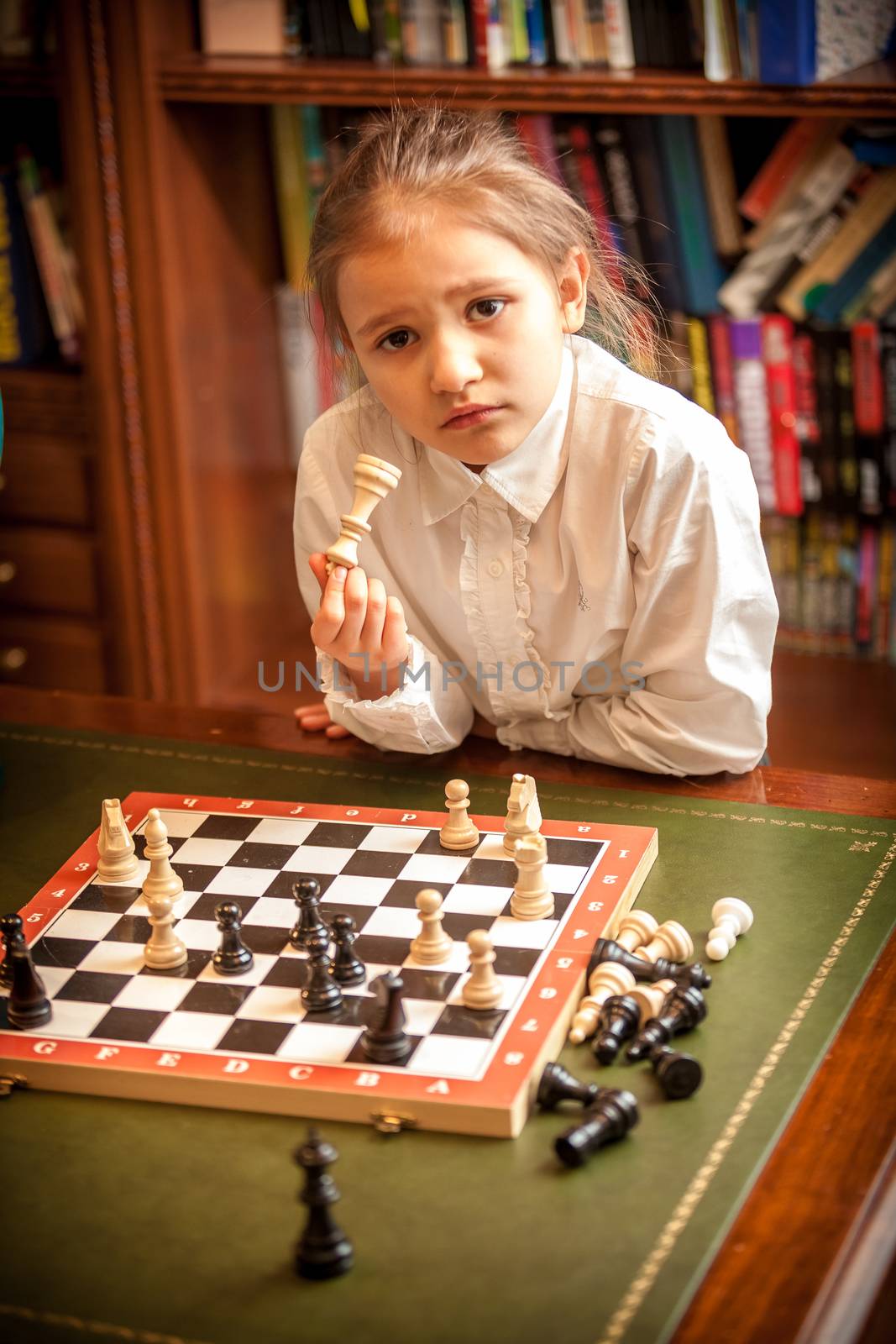 Girl in white shirt thinking on move at chess