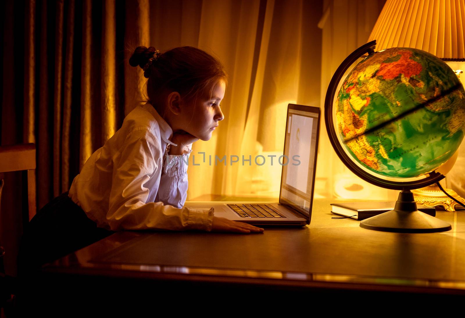 Girl looking at laptop screen at dark room