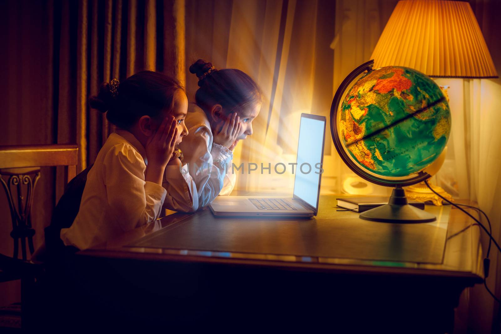 Girls looking with amazement at laptop at night