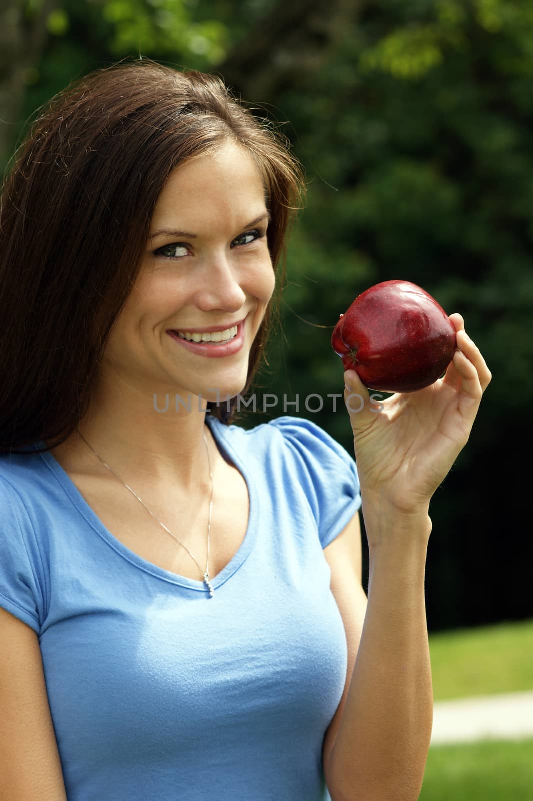 Attractive Woman Smiling in Park with Red Delicious Apple  by ChrisBoswell