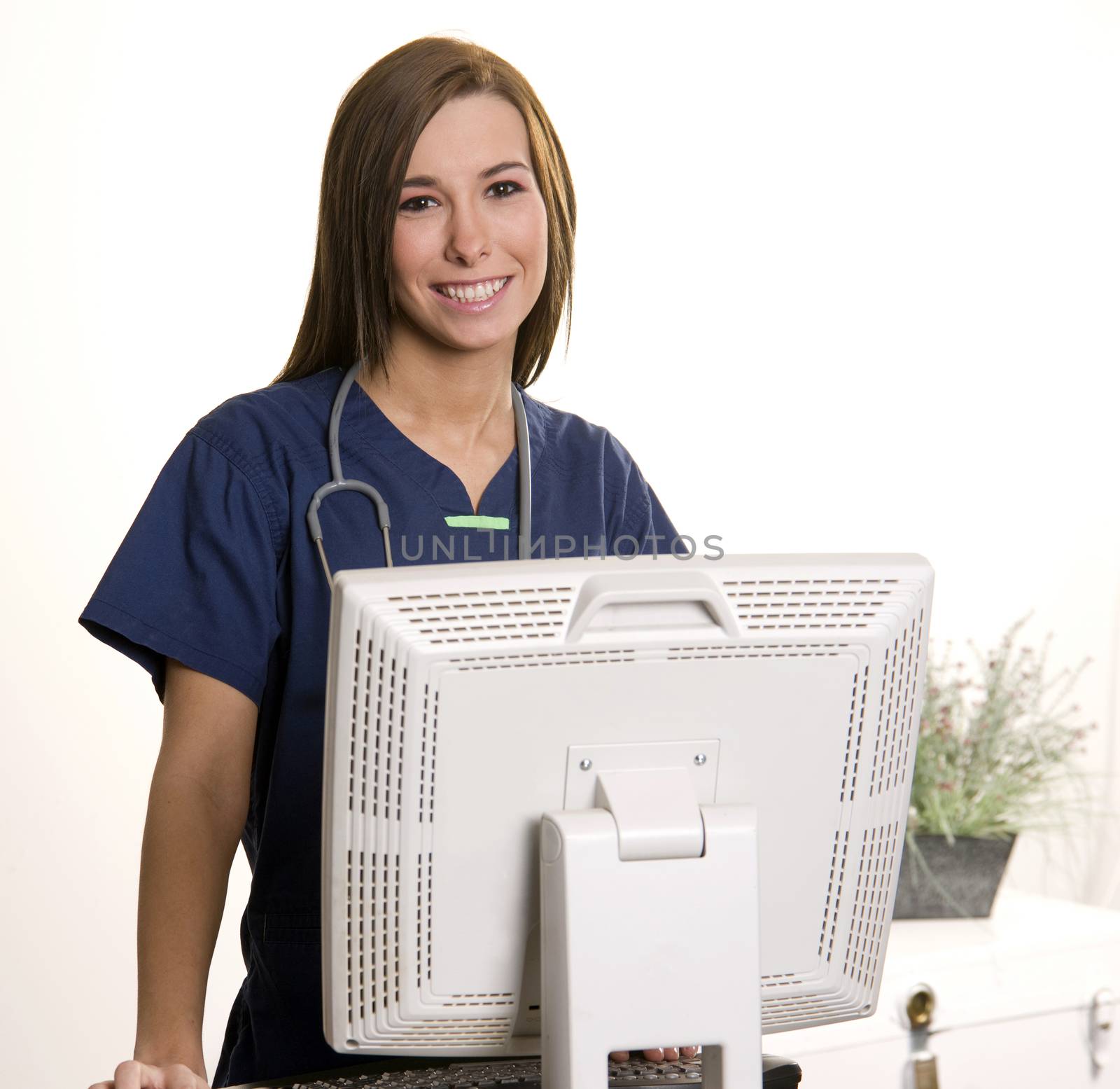 Working Nurse Smiles Looking over Monitor at Computer Workstatio by ChrisBoswell