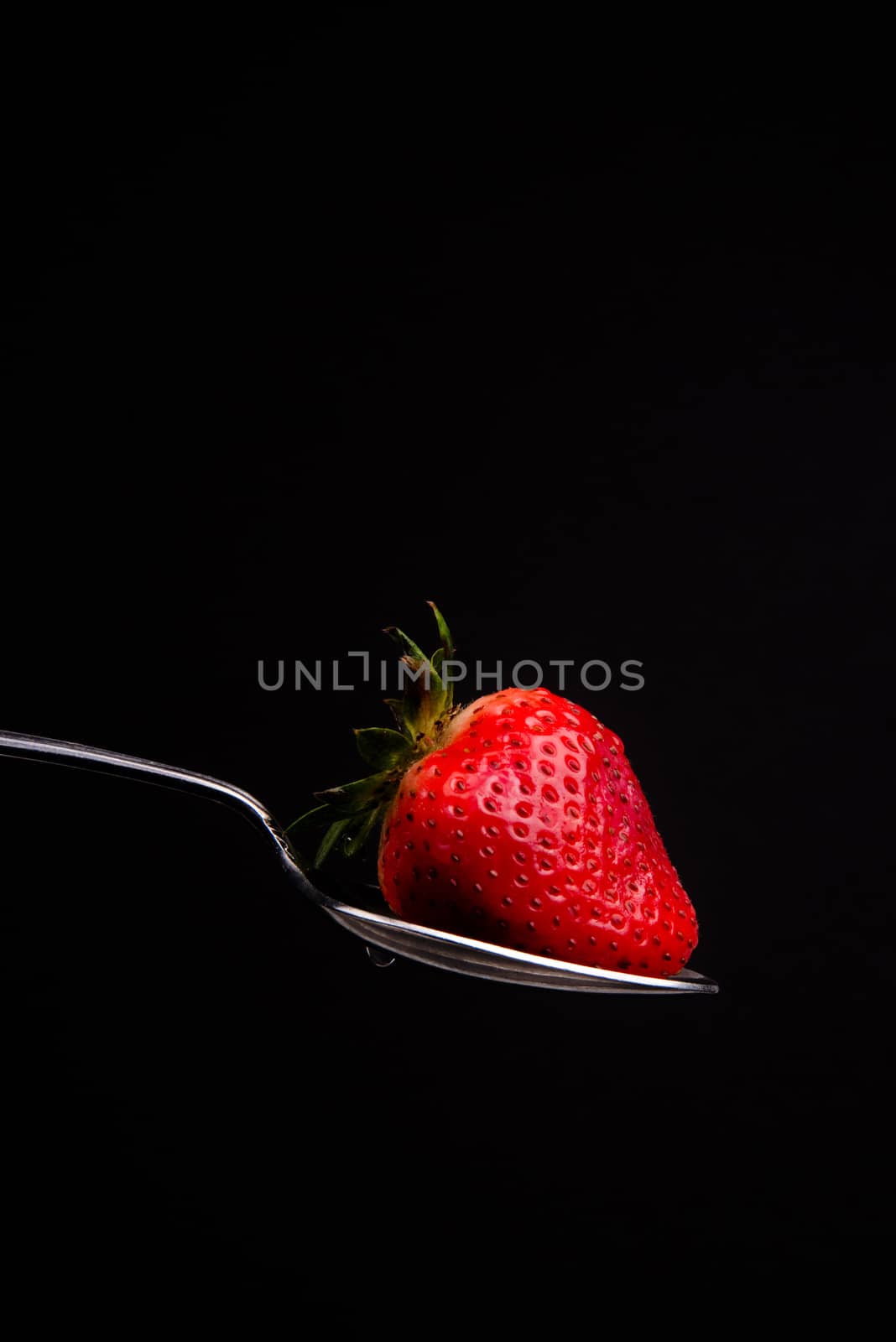 Red Raw Food Strawberry on a Silver Spoon on Black Background by ChrisBoswell