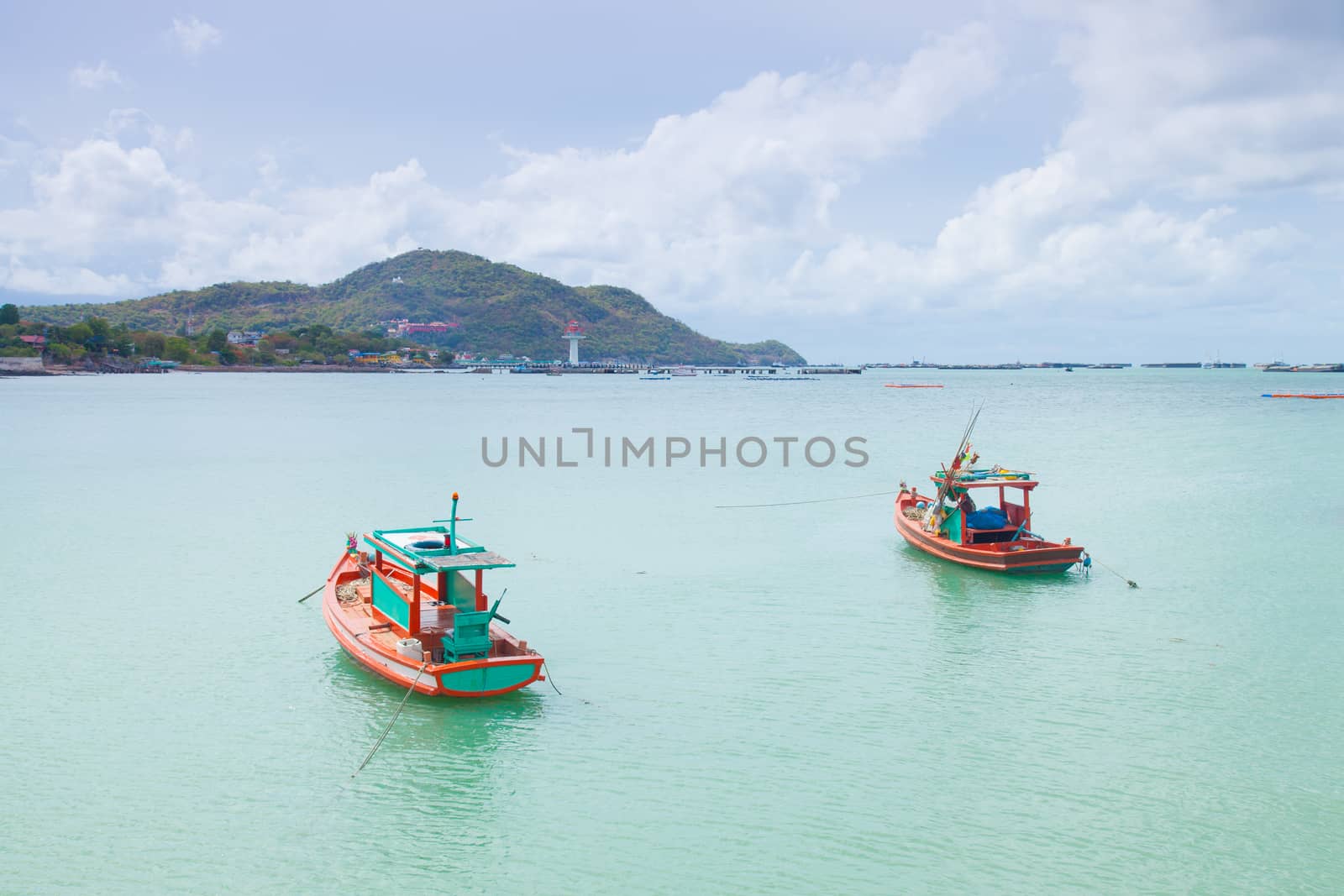 Small fishing boats moored in the sea. Behind the mountains and trees.