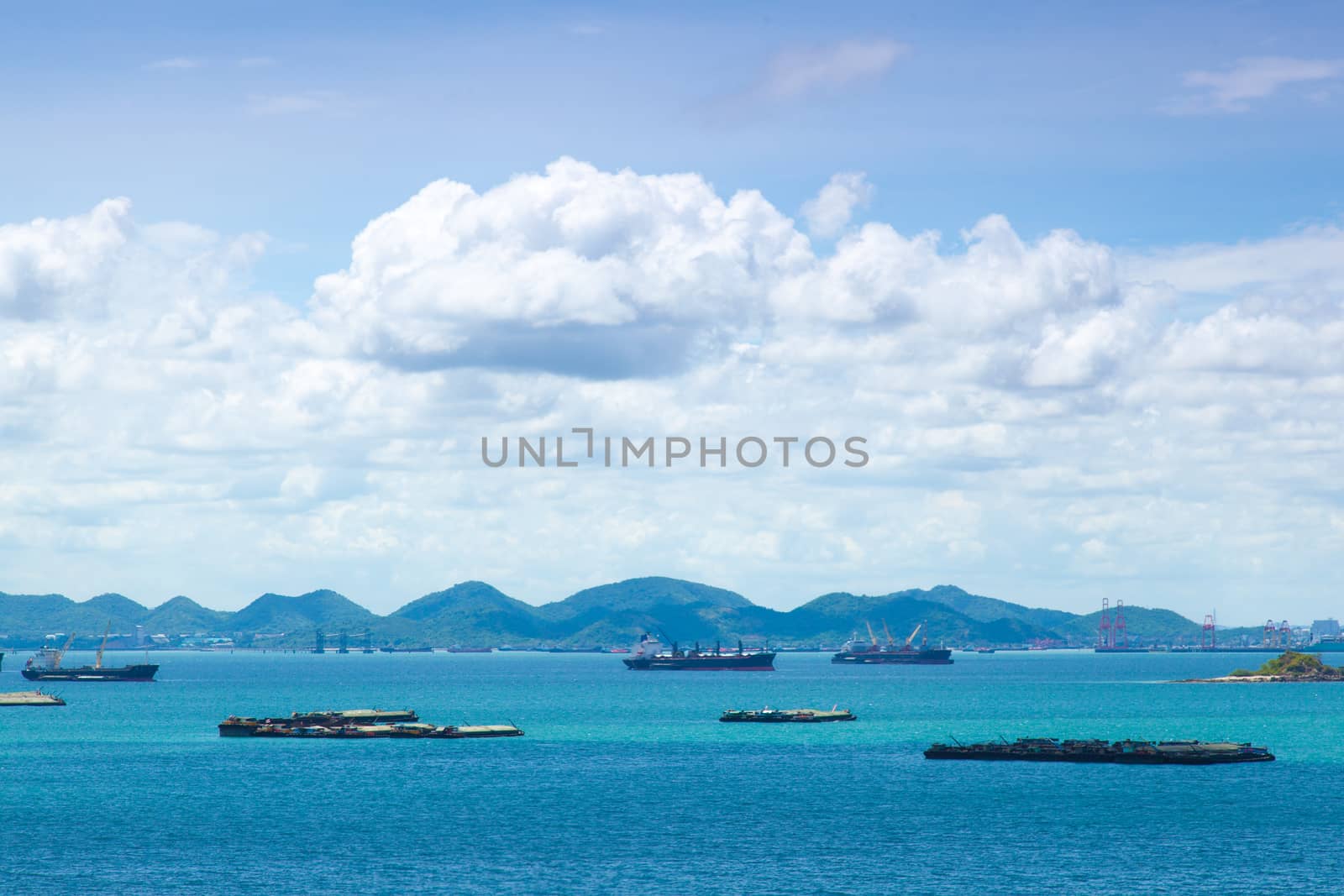 Cargo ships. Moored in the sea near the island. The bright sky in the daytime.