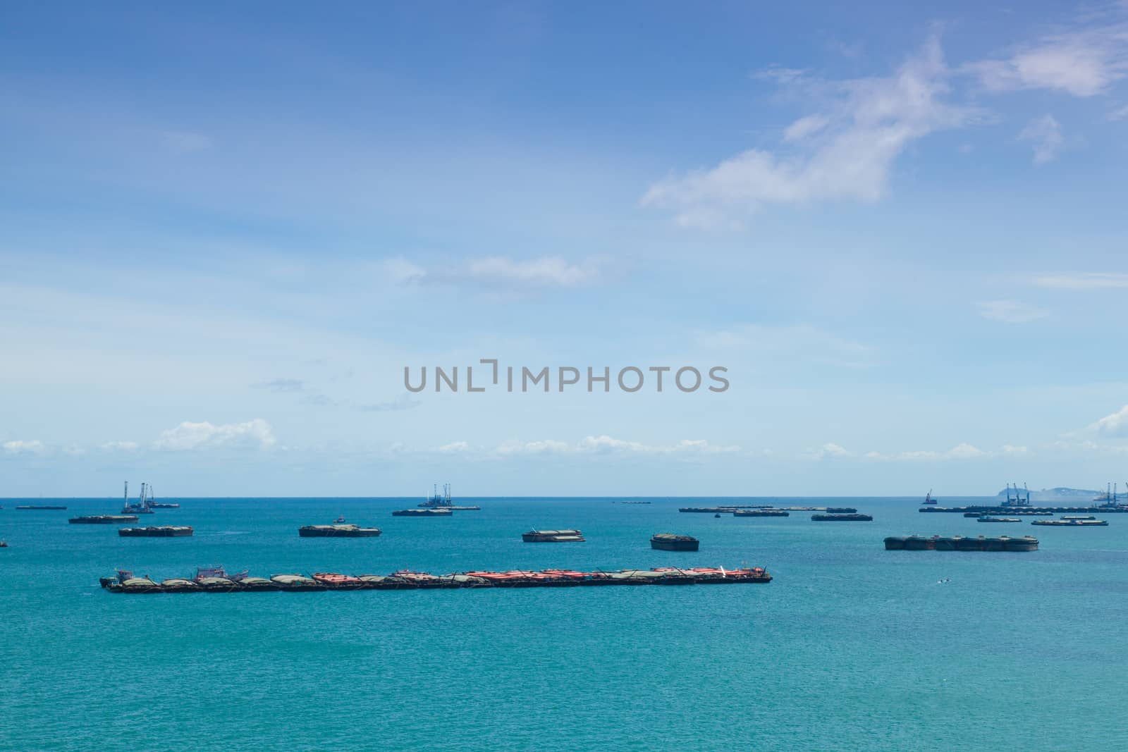 Cargo ships. Moored offshore. In the daytime sky with little clouds.