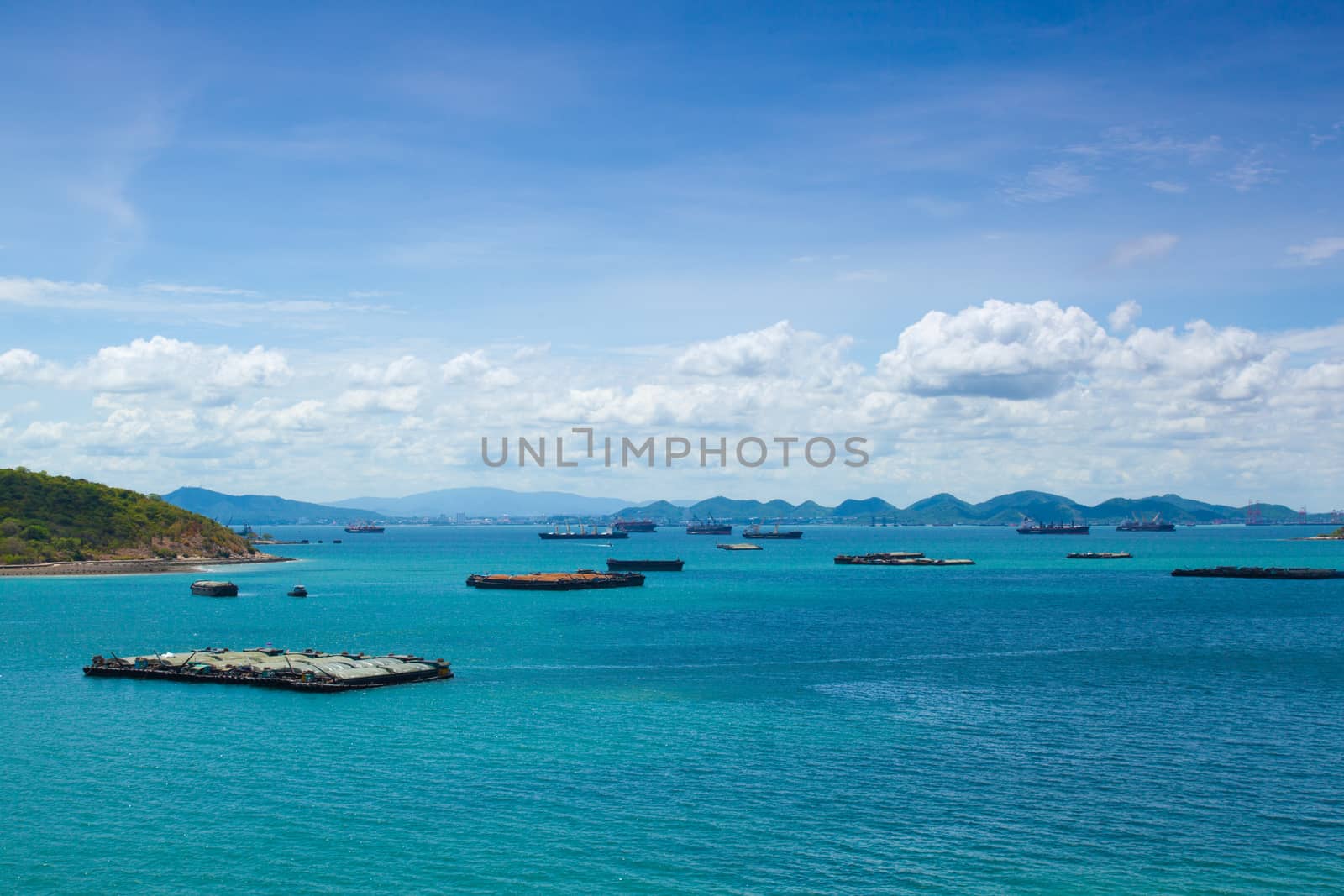 Cargo ships. Moored in the sea near the island. The bright sky in the daytime.