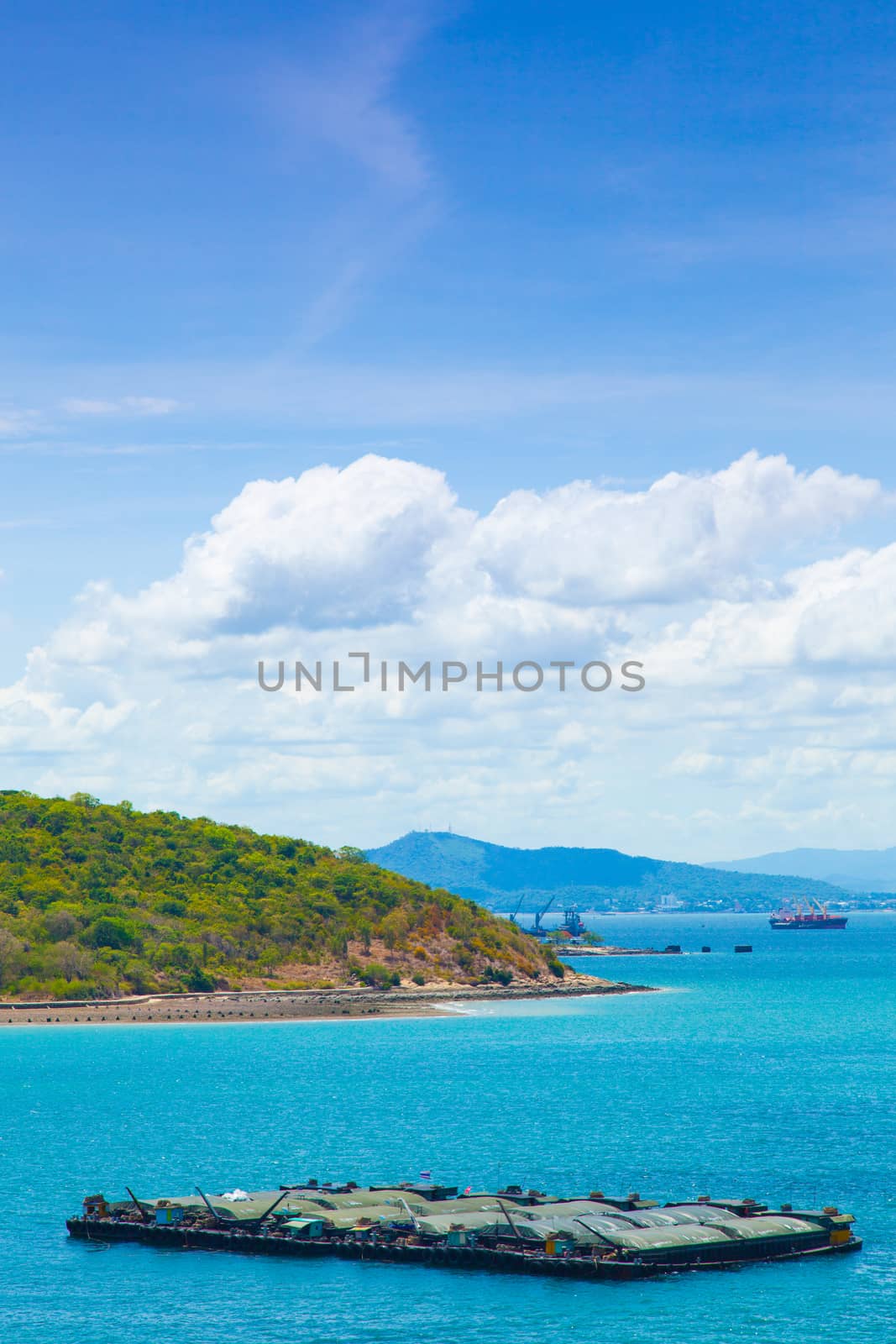 Cargo ships. Moored in the sea near the island. The bright sky in the daytime.