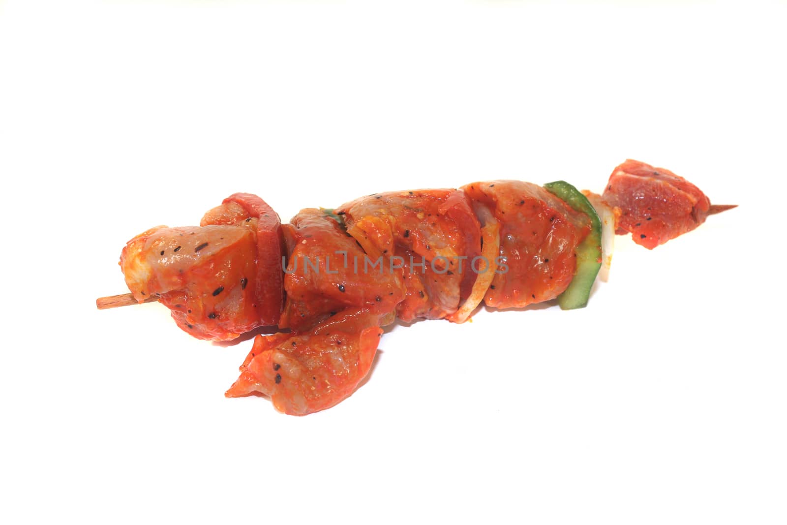 raw, marinated skewered meat in front of white background