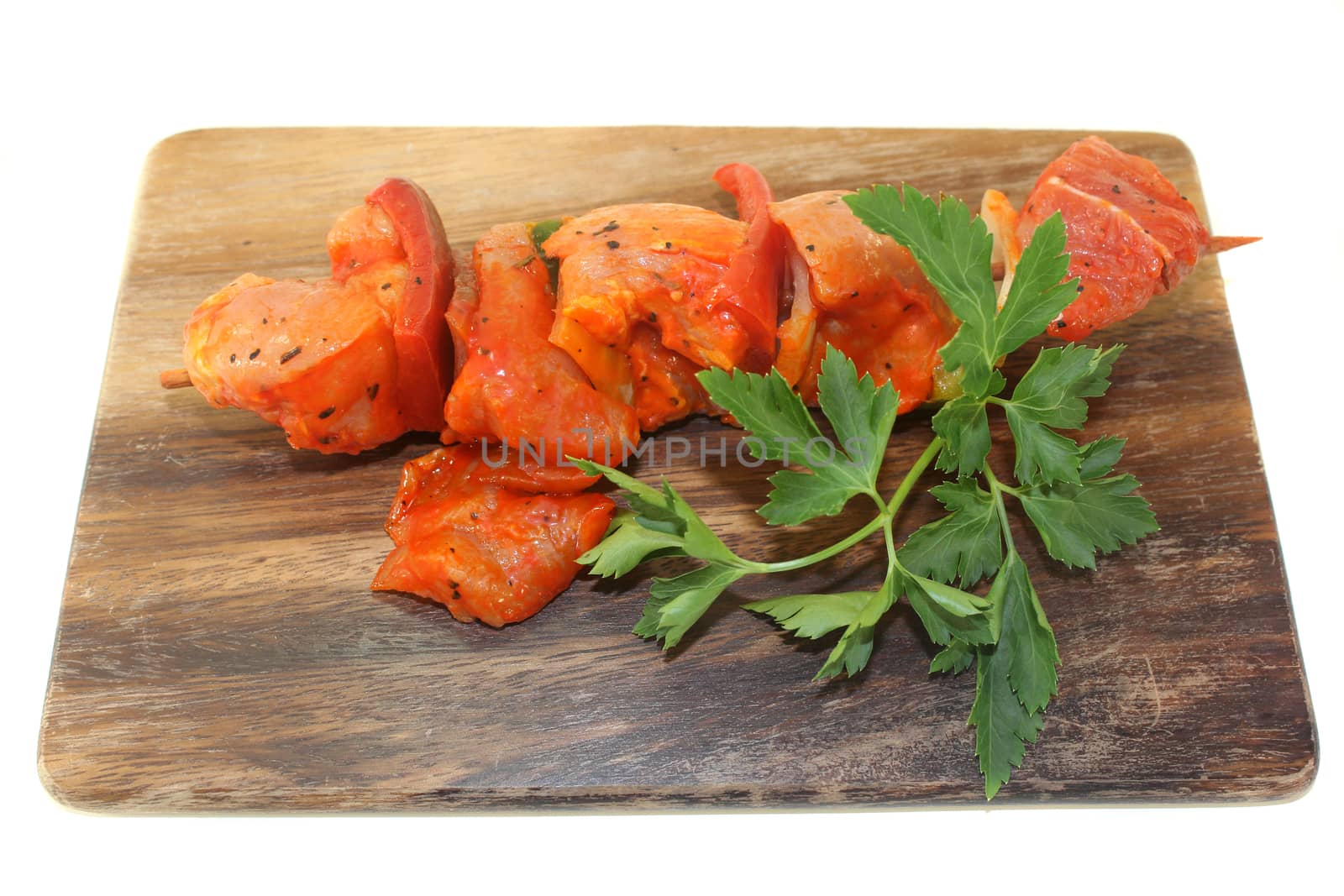 raw, marinated skewered meat in front of white background