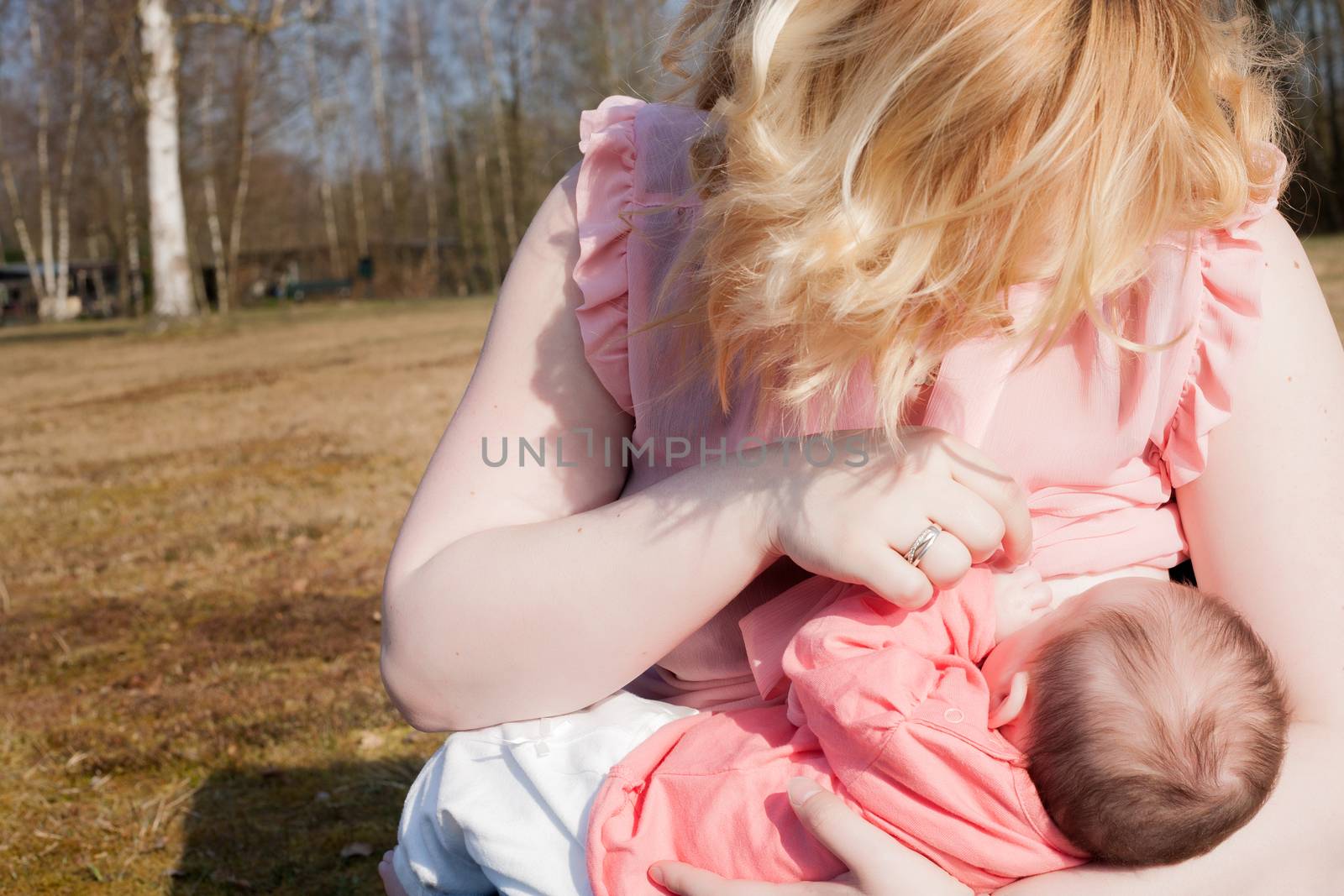 Mother is feeding her baby on the field