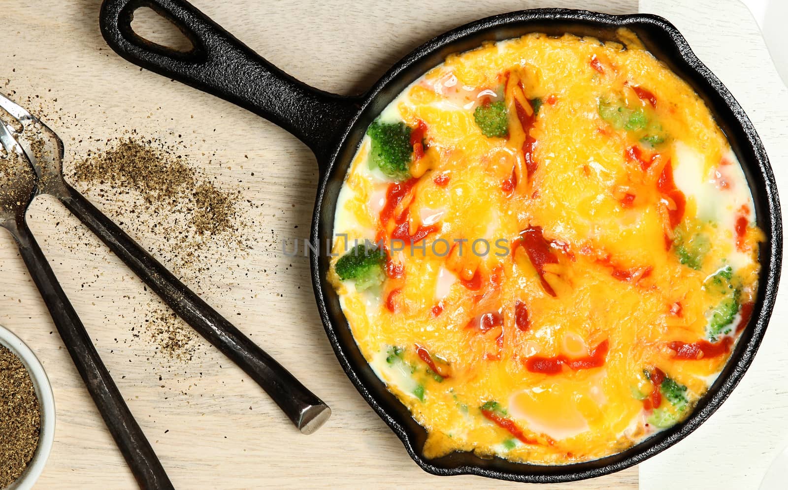 Skillet Baked Eggs with Brocoli, Cheese, Sriracha Sauce on Table.