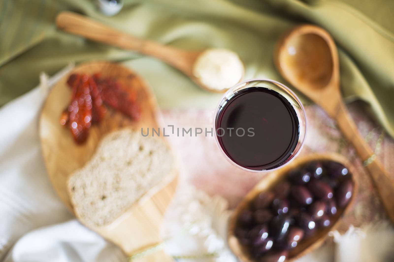 Red wine in glass from directly above with tapas out of focus on table.