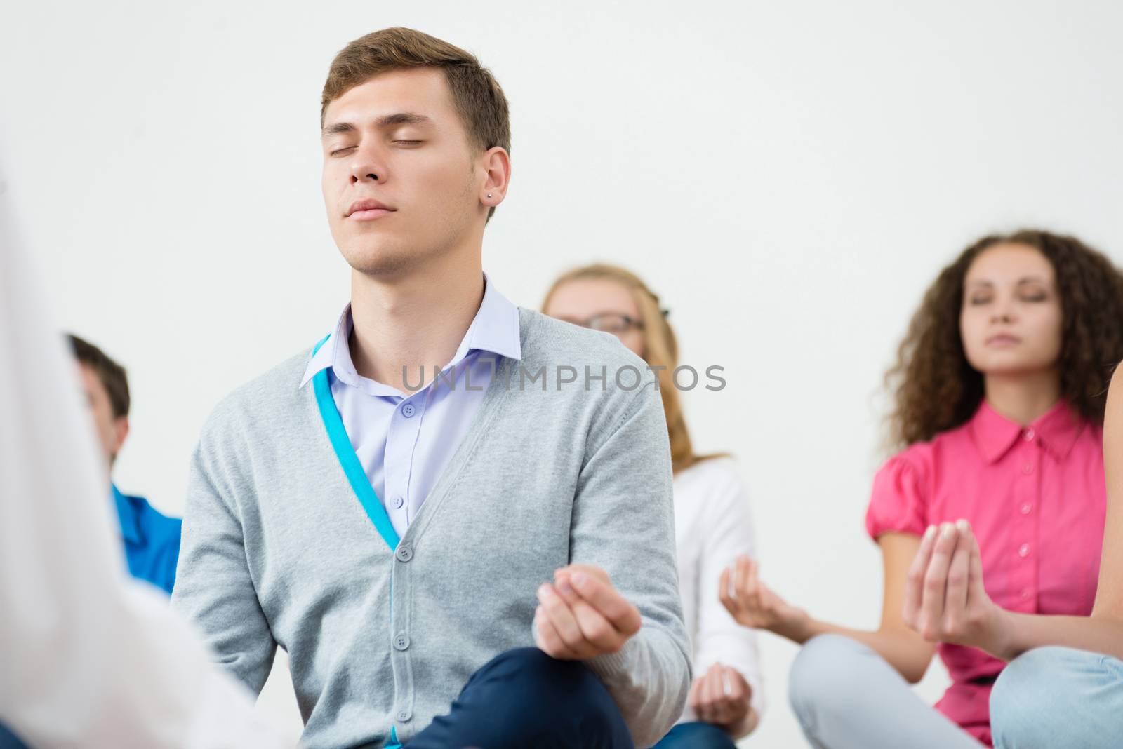 group of young people meditating in office at desk, group meditation