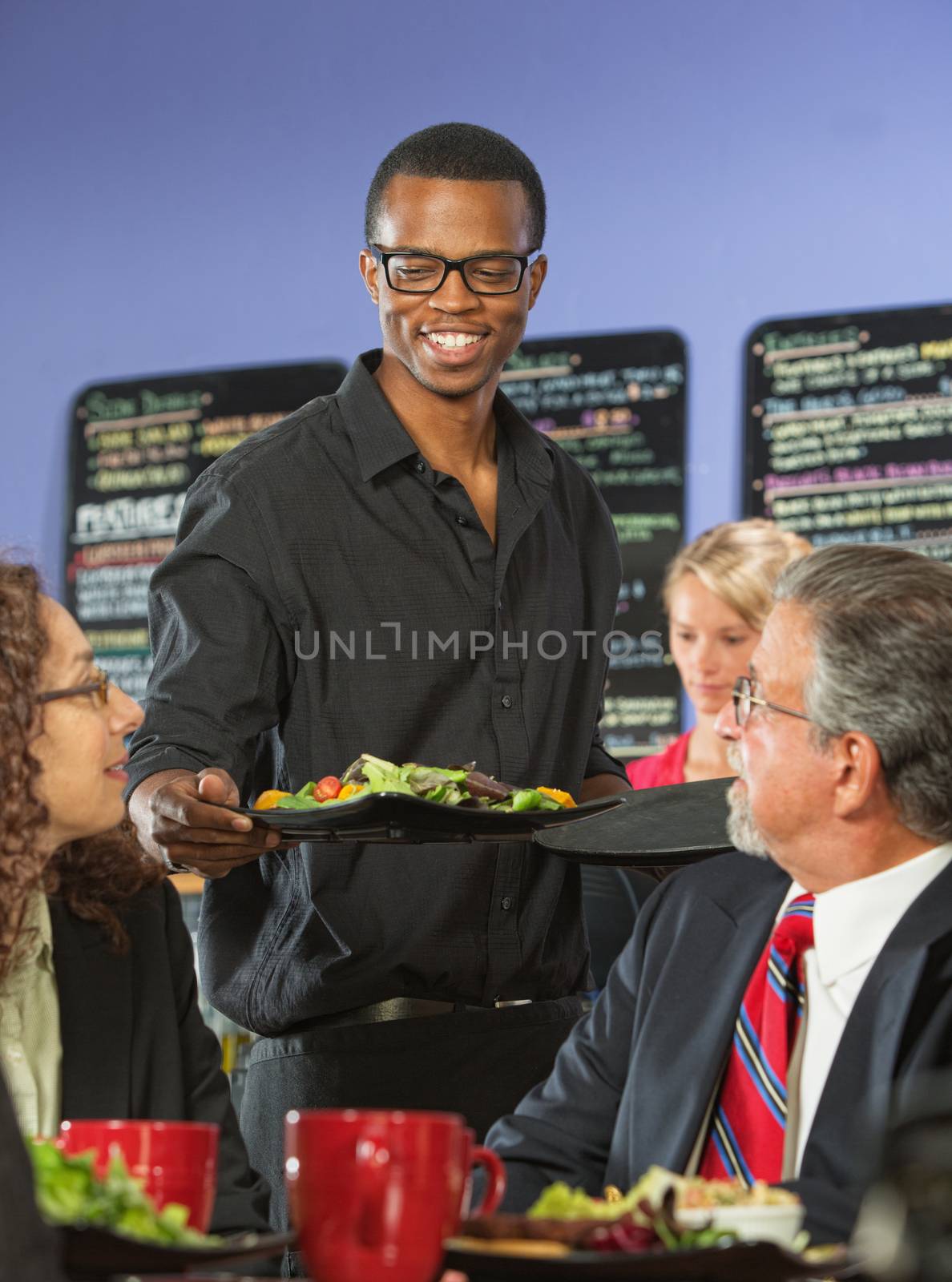 Handsome coffee house barista serving group of executives