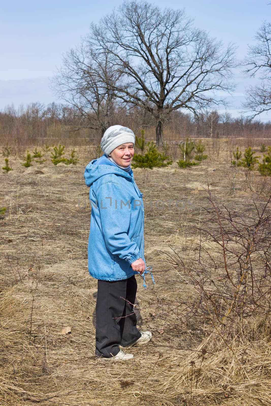 One elderly woman in a spring forest walks