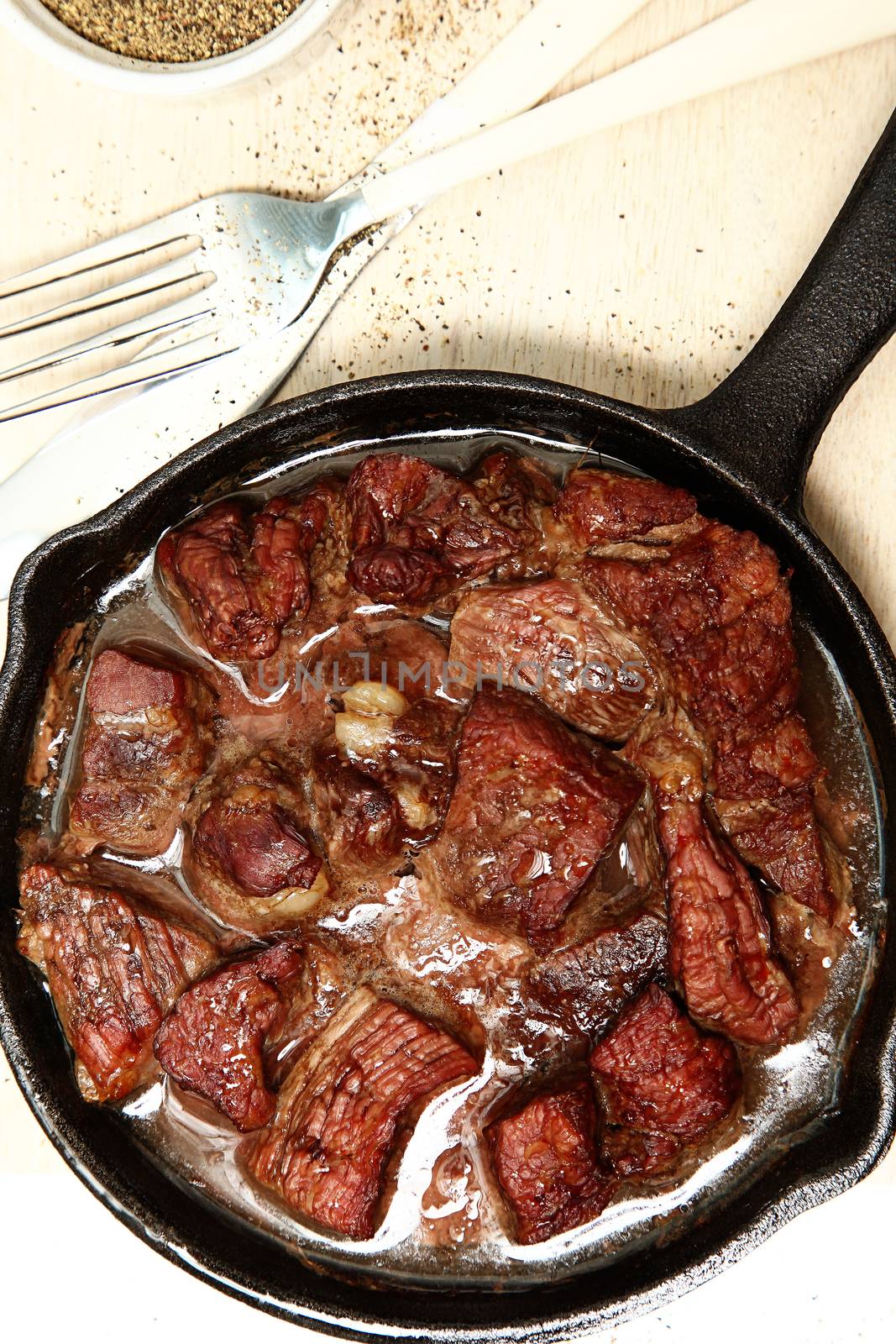 Oven Baked Beef Cubes in Cast Iron Skillet at table or restaurant.