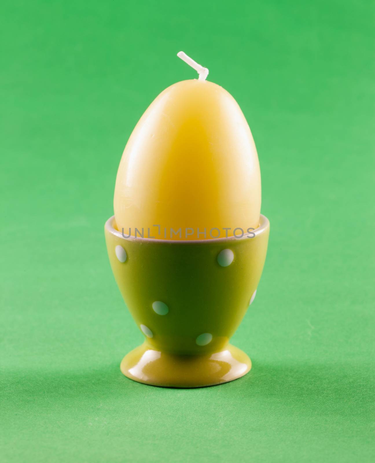 Yellow candle in shape of egg over green