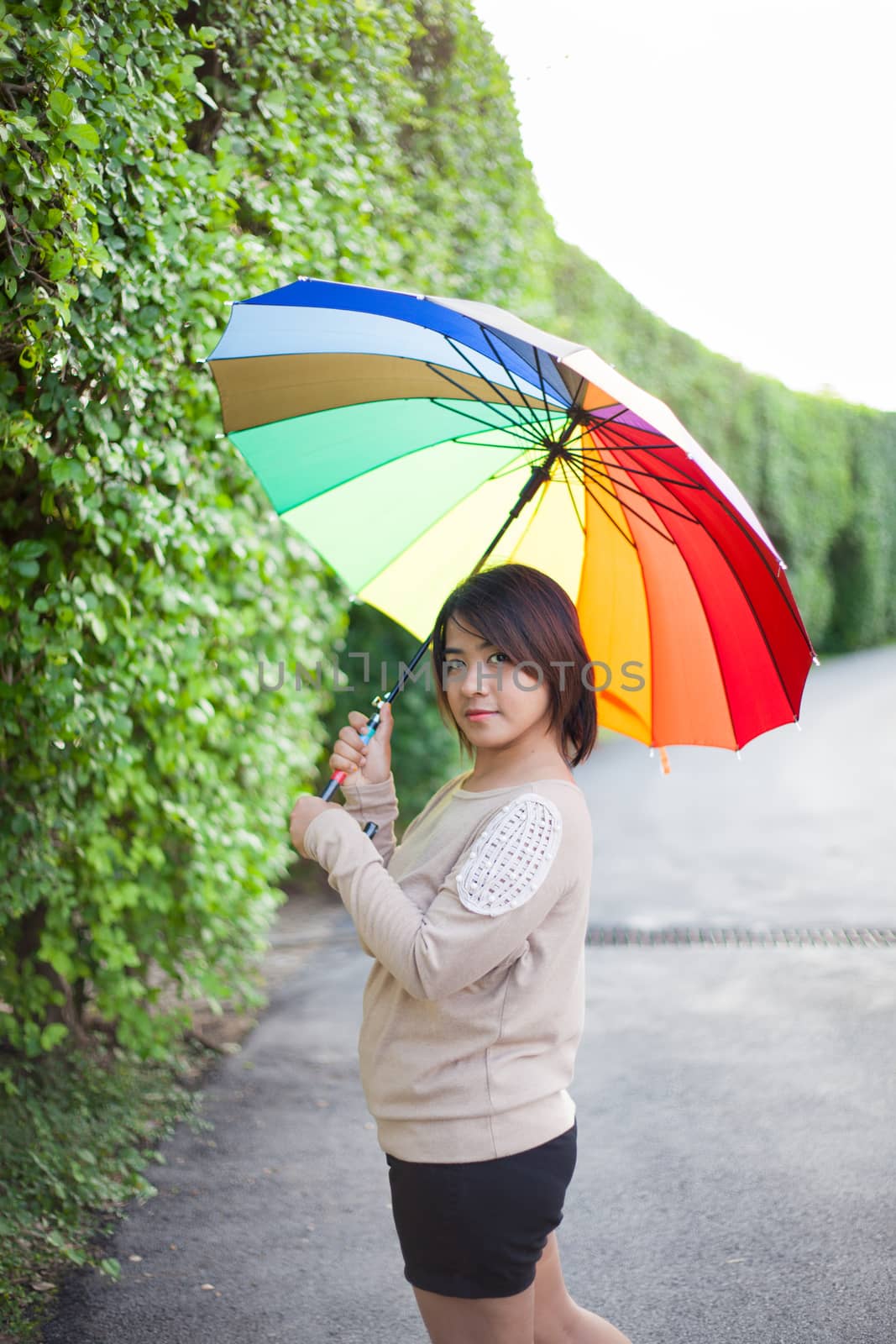 Asian woman holding an umbrella on the sidewalk. by a454