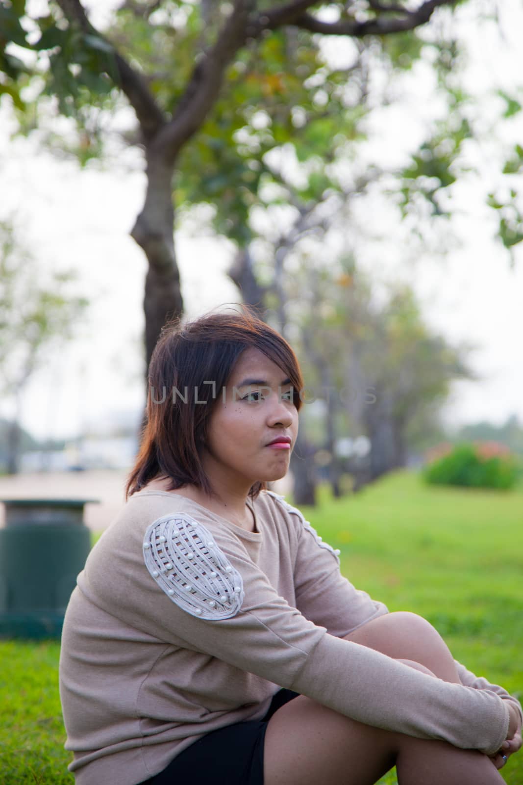Portrait Asian woman sitting in the park. Sitting on fresh grass.