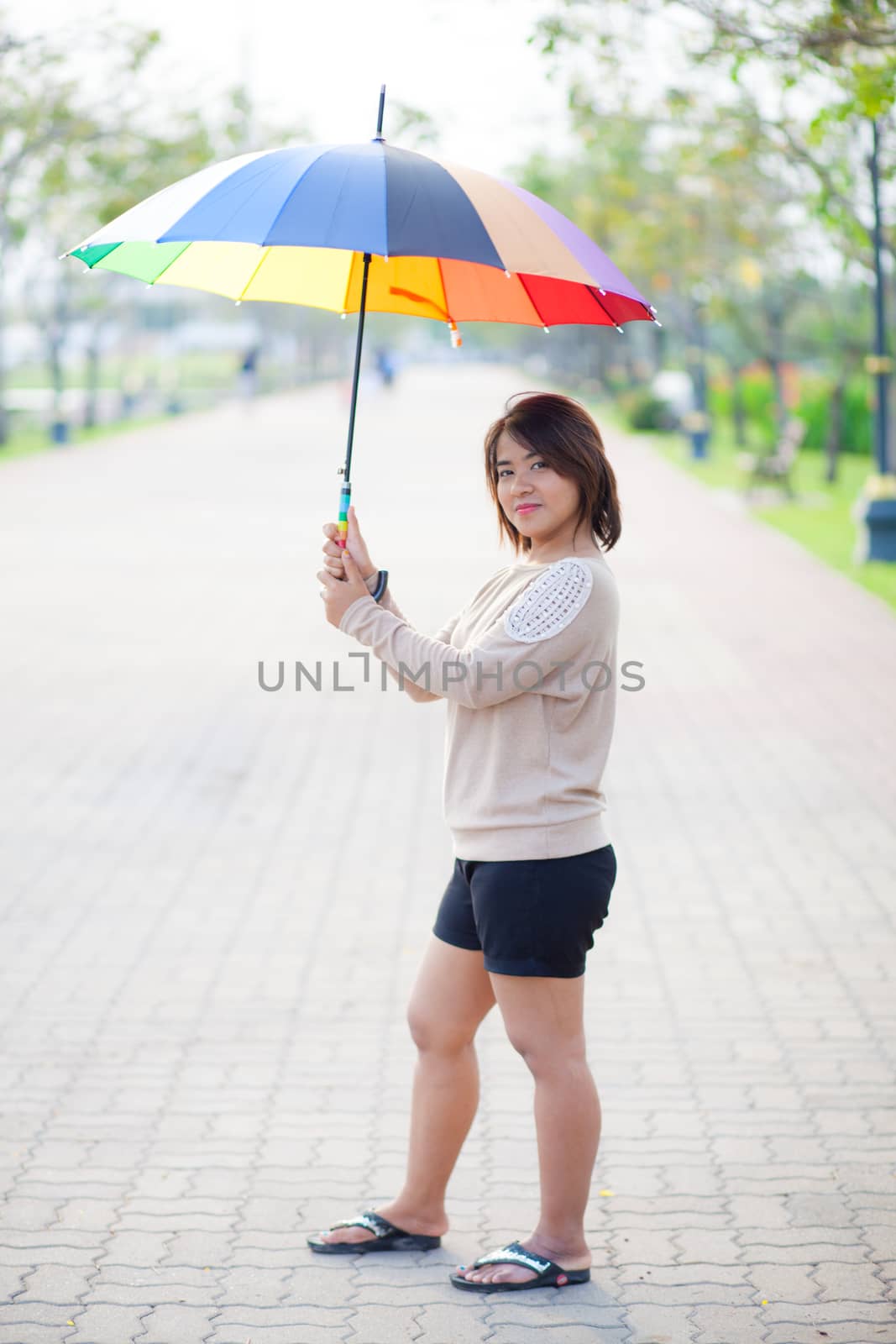 Portrait Asian woman holding an umbrella. On the path within the park.