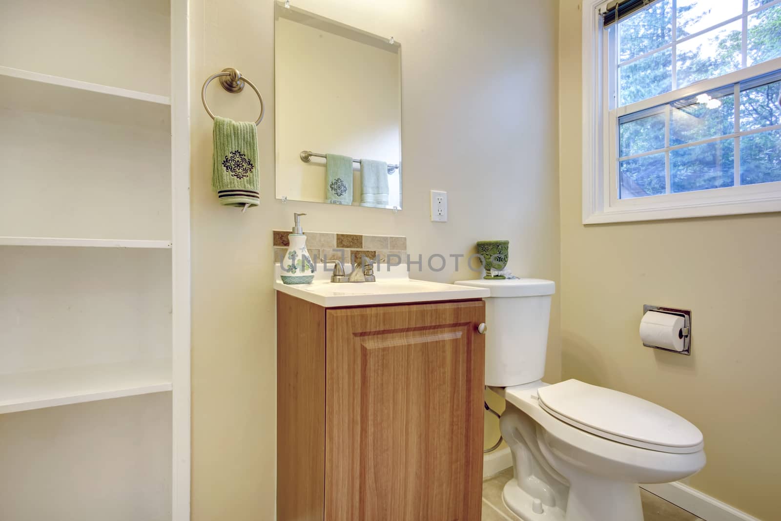 Light tones bathroom with french window. View of washbasin cabinet, toilet and built-in shelves