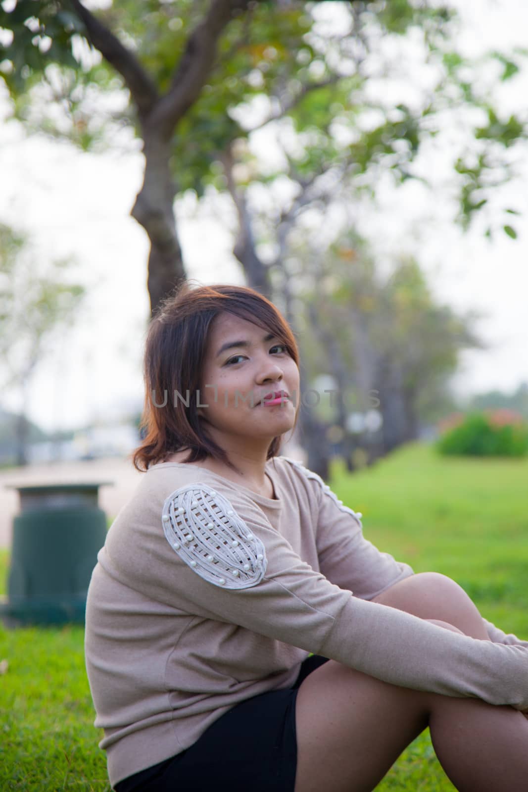 Portrait Asian woman sitting in the park. Sitting on fresh grass.