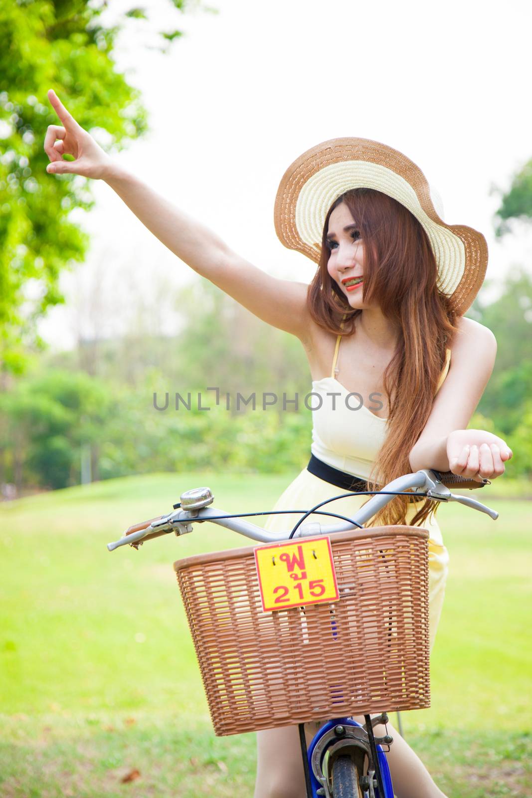 asian woman riding bikes and looking above. The hand was pointed to above it in the park.