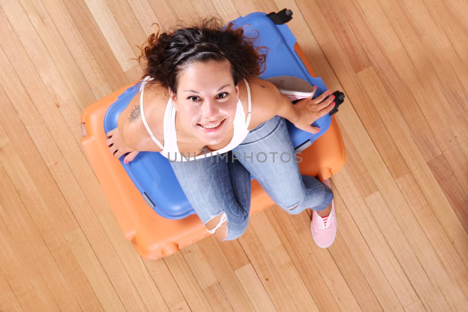 A young woman sitting on a stack of suitcases.