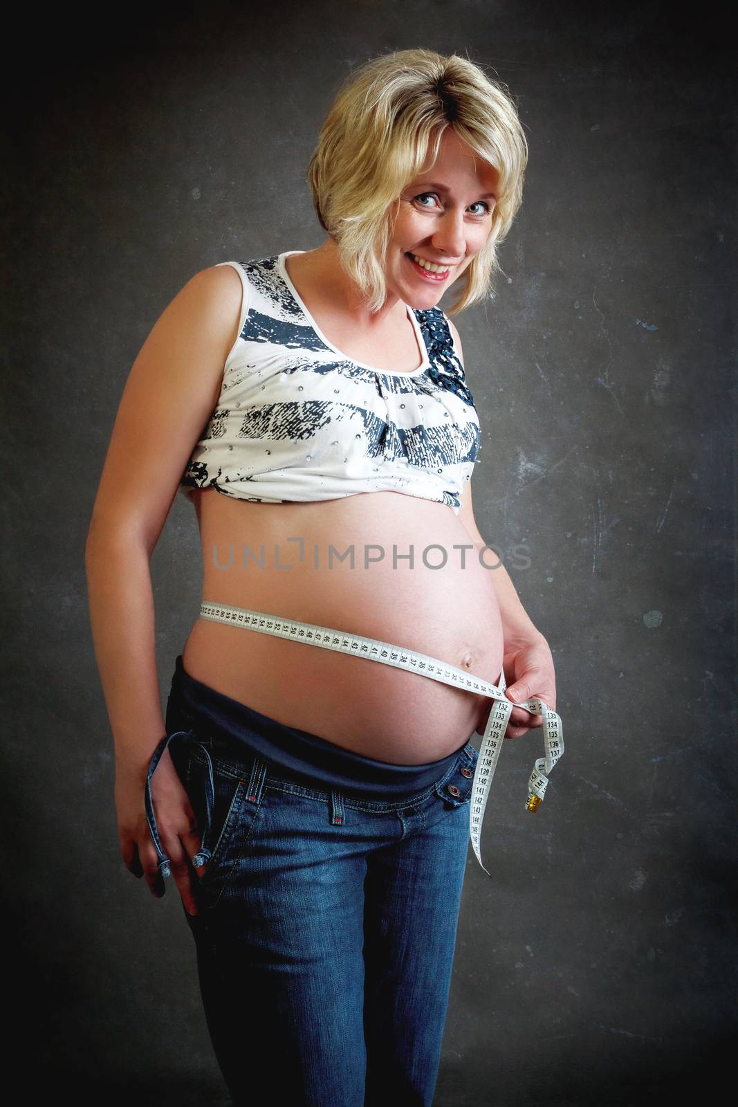 beautiful smiling pregnant woman tenderly measuring her tummy