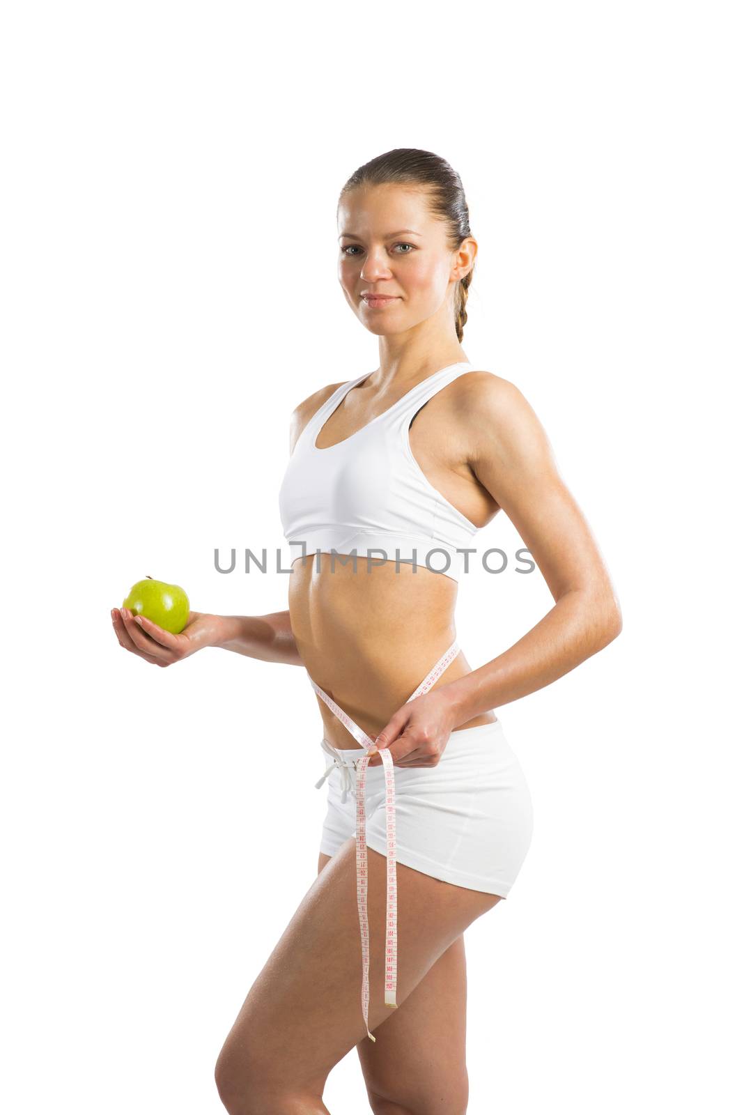 young athletic girl measuring waist measuring tape and holding a green apple, concept of healthy eating, isolated on white background