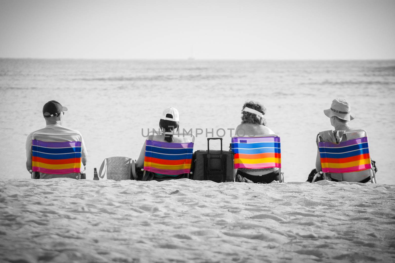 Group Of People On Colorful Deckchairs Against Black And White Beach